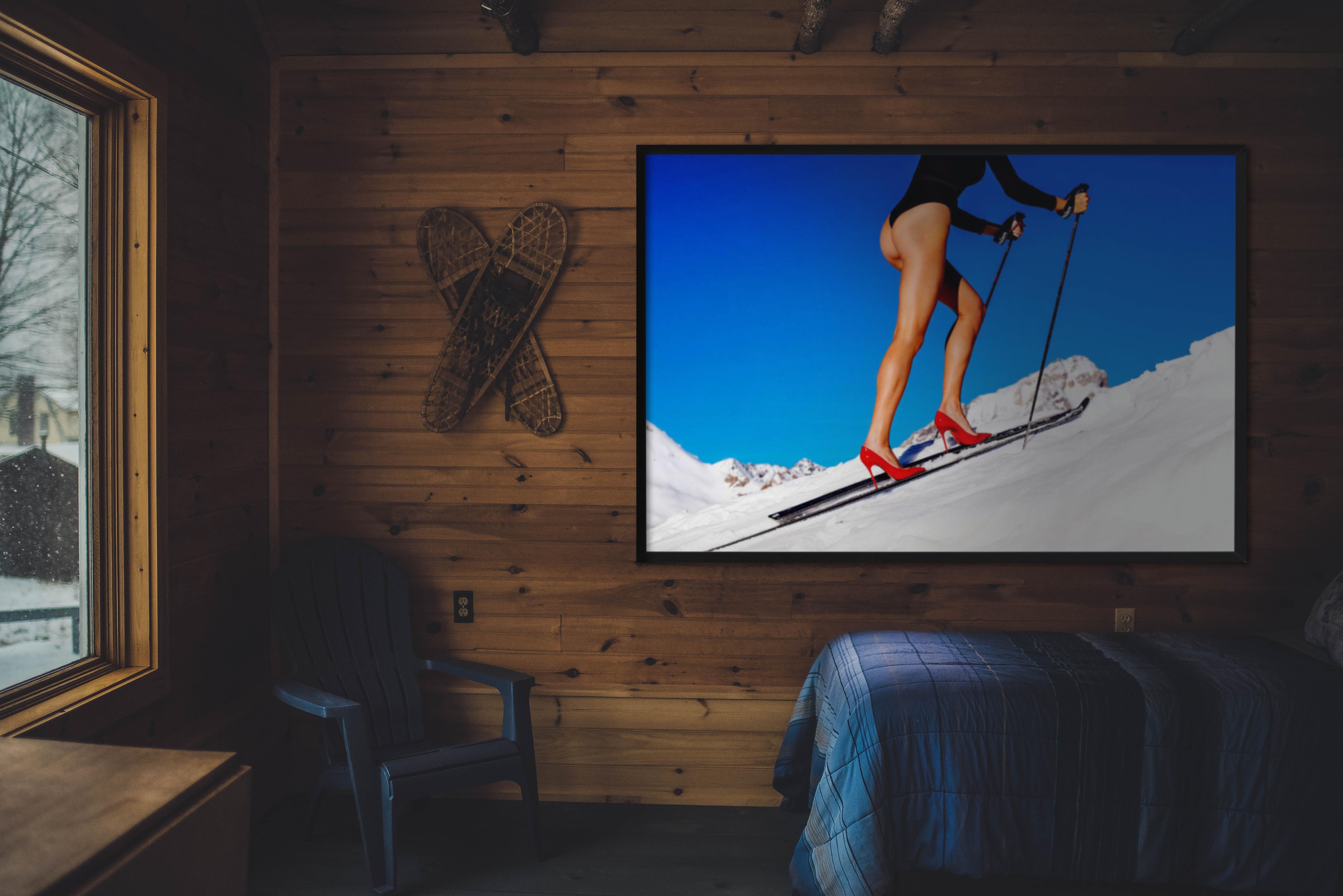Modella con un body nero che scala una montagna innevata con tacchi alti rossi attaccati a un paio di sci, fotografata da Tony Kelly nel 2018.

Tutte le stampe sono in edizione limitata. Disponibile in più misure. Cornici di alto livello su