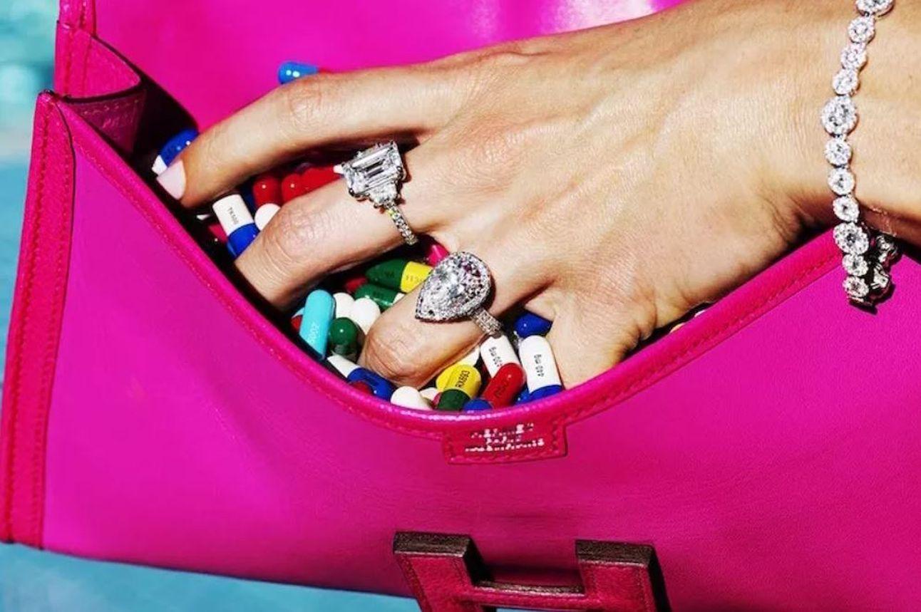 Beverly Hills Pills - a hand grabing pills out of  a pink bag
