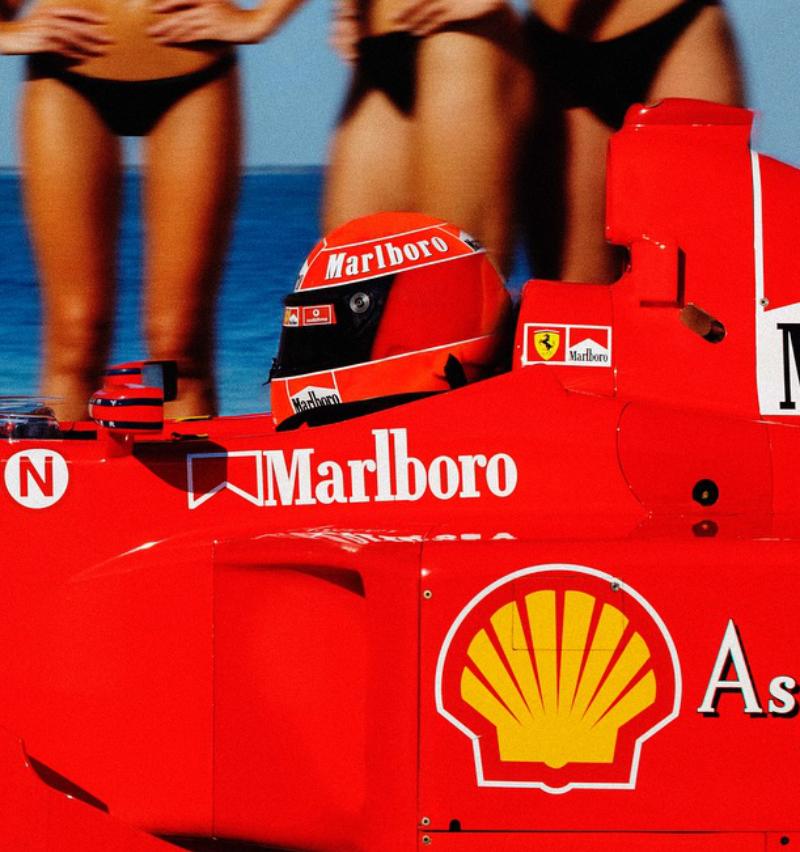 Una Ferrari F1 rosso brillante passa davanti a un gruppo di donne abbronzate in bikini nero in riva all'oceano, fotografate da Tony Kelly nel 2024

Tutte le stampe sono in edizione limitata. Disponibile in più misure. Cornici di alto livello su