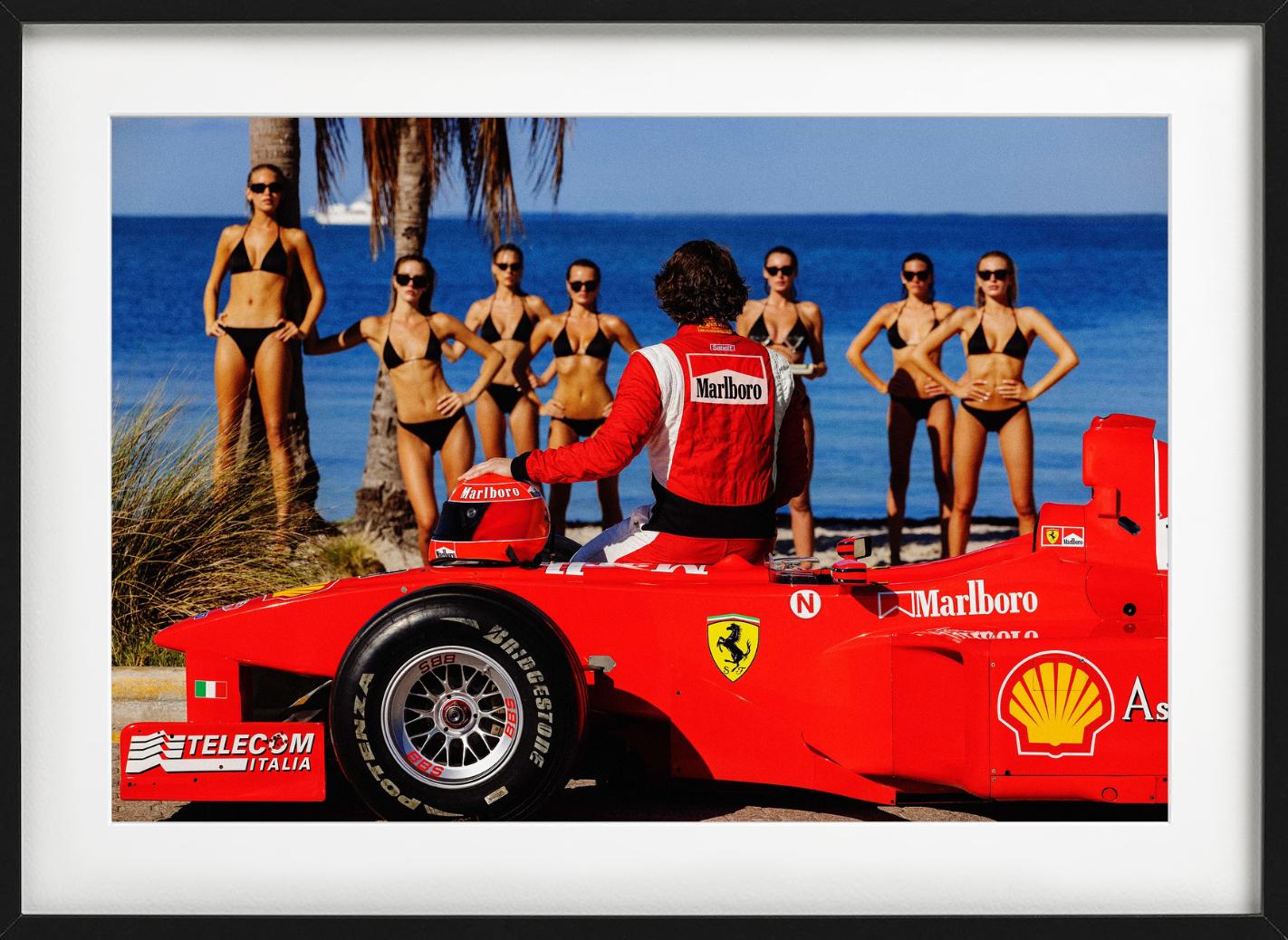 El conductor de un Ferrari F1 rojo brillante está sentado en su coche, mirando a un grupo de mujeres bronceadas en bikini negro junto al océano, fotografiado por Tony Kelly en 2024.

Todas las impresiones son de edición limitada. Disponible en