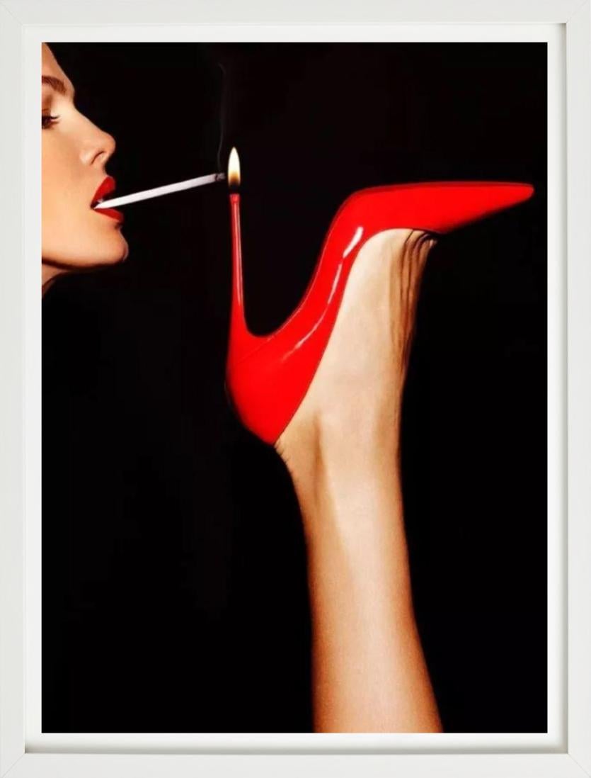 Super Slim - roter Schuh mit einer Frau, die ihre Zigarettenflasche beleuchtet, Kunstfotografie – Photograph von Tony Kelly