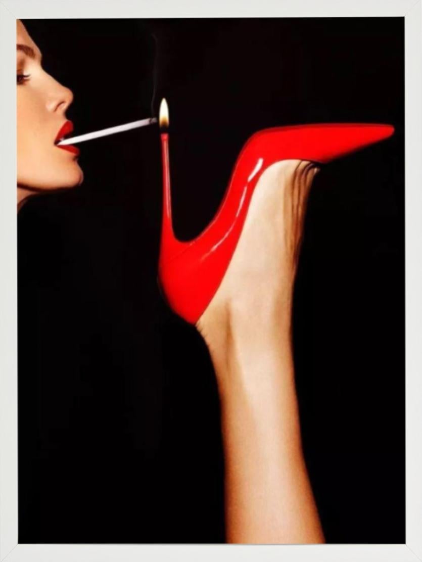Super Slim - roter Schuh mit einer Frau, die ihre Zigarettenflasche beleuchtet, Kunstfotografie (Zeitgenössisch), Photograph, von Tony Kelly
