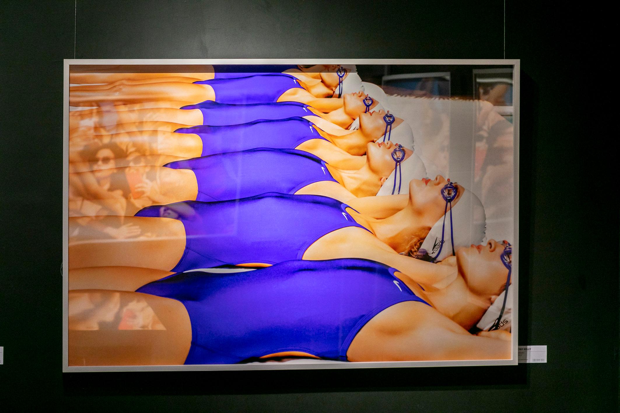 TK Swimteam - colourful portrait of women sunbathing in blue swimsuits - Photograph by Tony Kelly