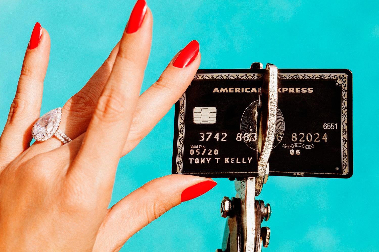 Tony Kelly Still-Life Photograph - Unbreakable - portrait of hand with red fingernails destroying a credit card