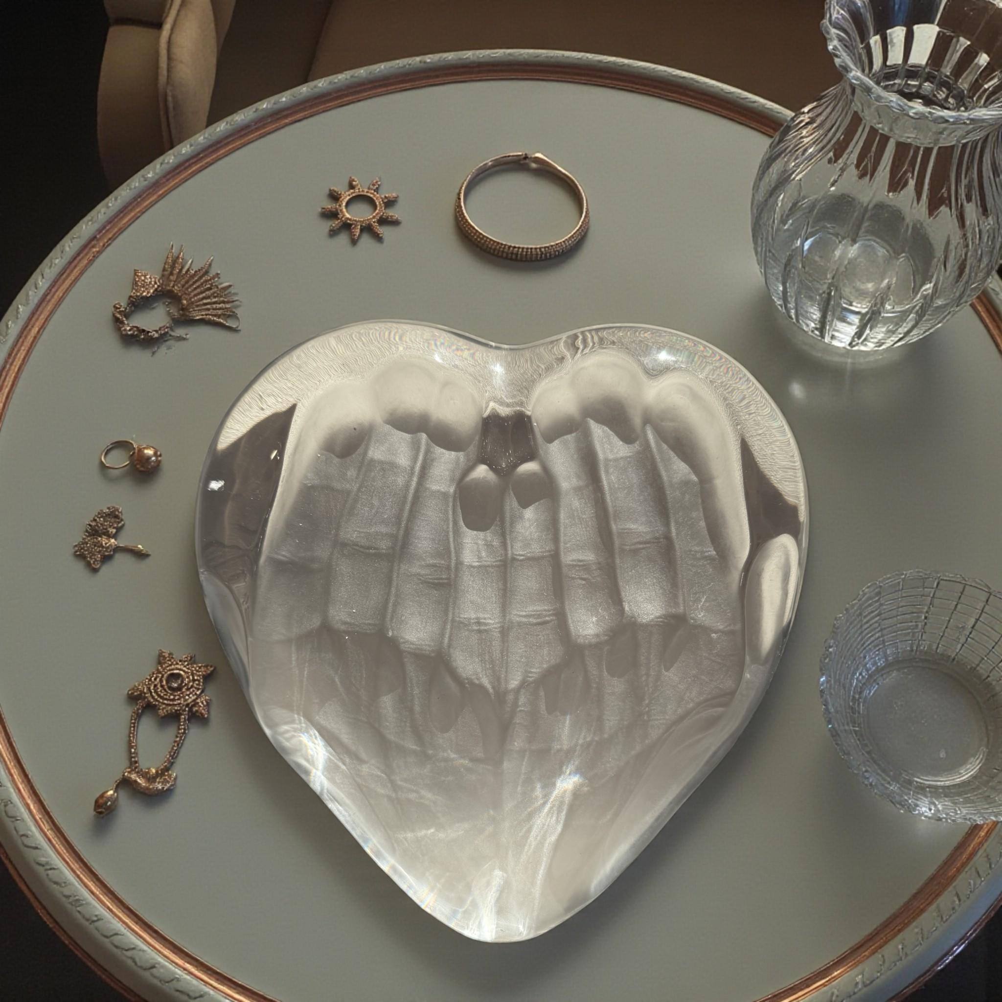 Espressione poetica di unit�à e cura, questa scultura in cristallo modellato e parzialmente smerigliato presenta un cuore delicatamente sostenuto da mani intrecciate. Disegnato dall'artista britannico Tony Morgan (1938-2004) per la rinomata casa di