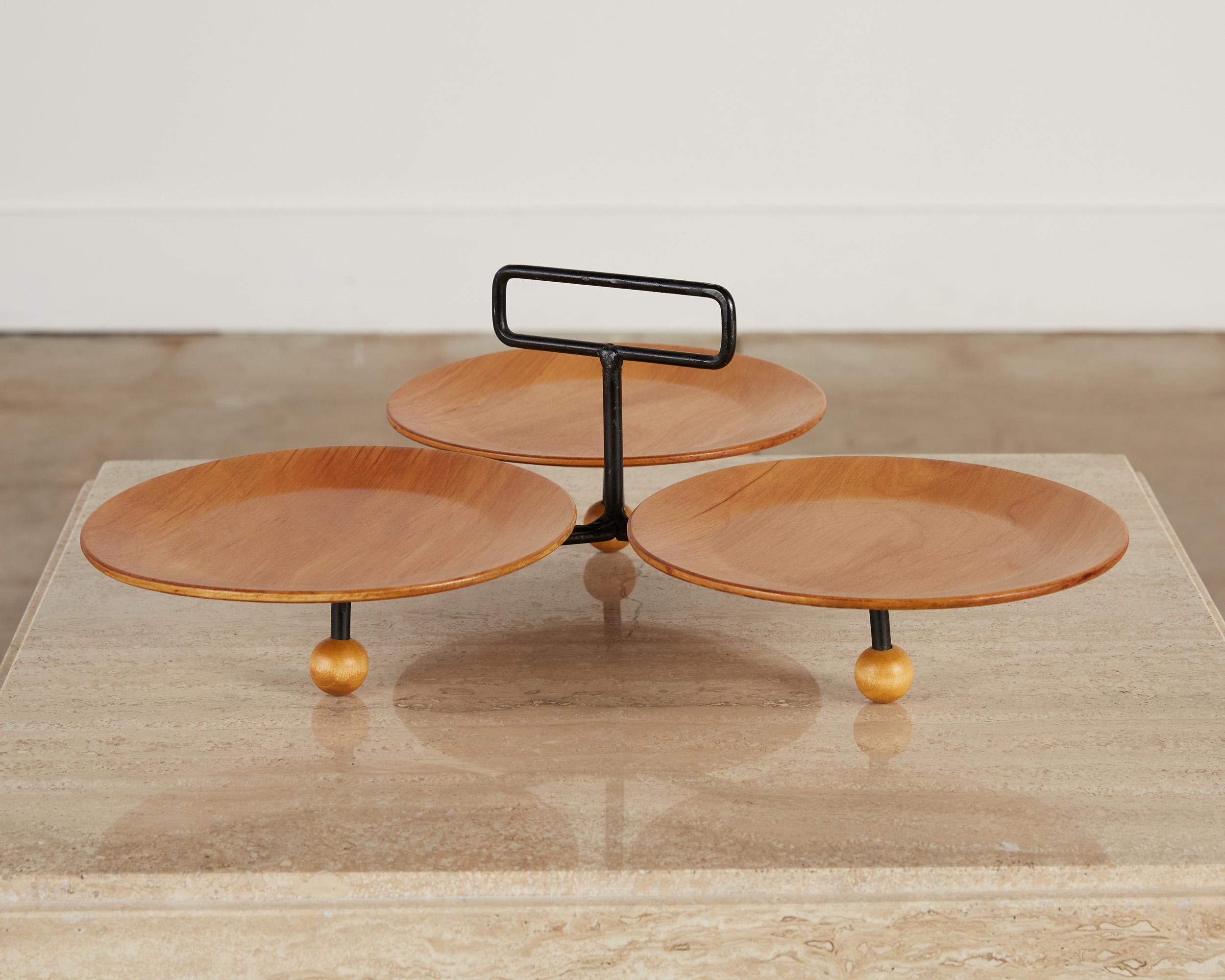 Three plate serving tray by Tony Paul, USA, c.1950s. The tray features a trio of circular concave wood disks that are supported by an iron frame with wooden ball feet. There is a rectangular iron handle that comes up from the frame in the middle of