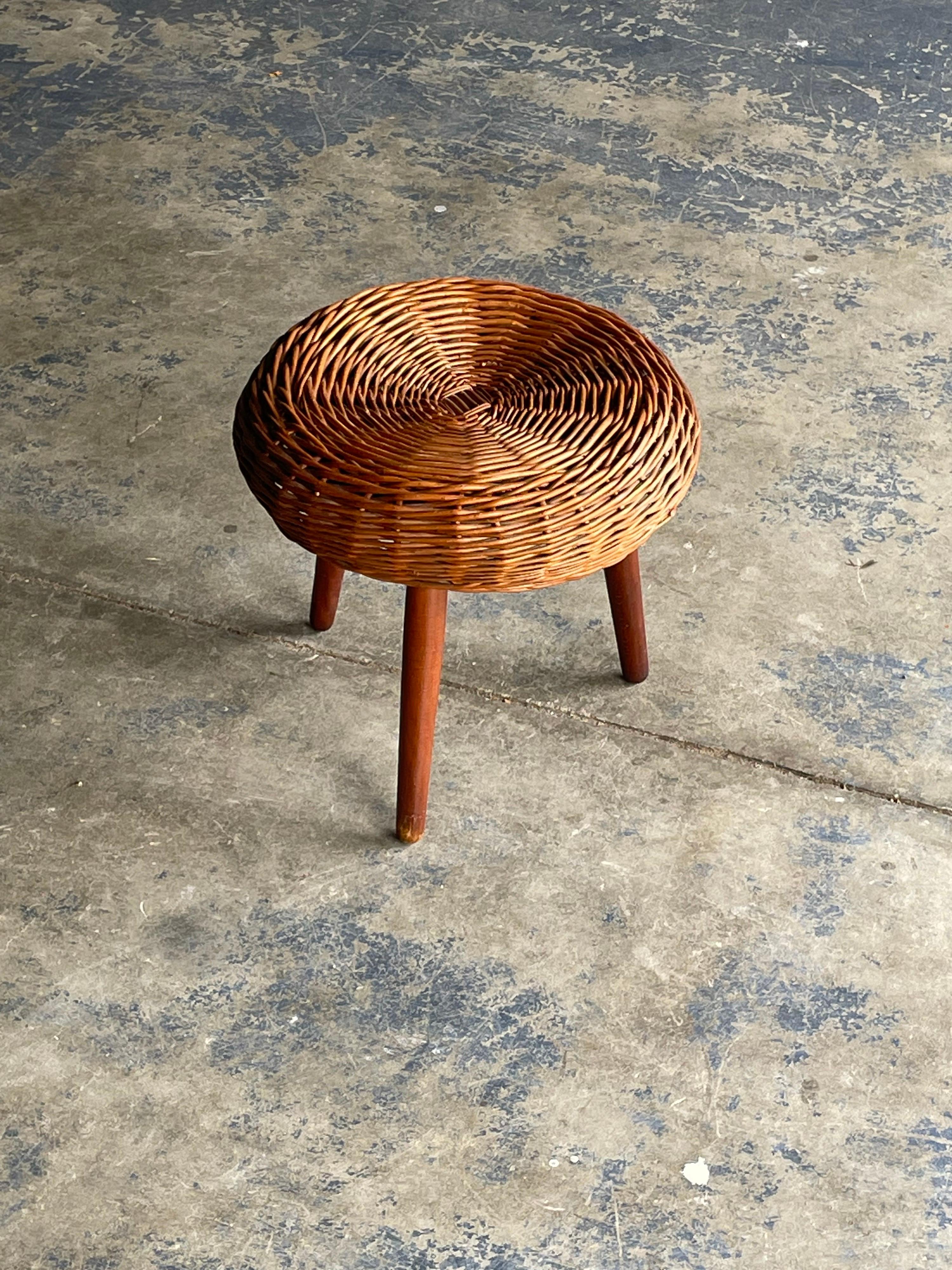 A rattan/ wicker topped stool with solid wood legs attributed to Tony Paul. Blends well with organic and minimalist design.

Please note that while these are commonly regarded as stools I would advise against putting full body weight on it. I