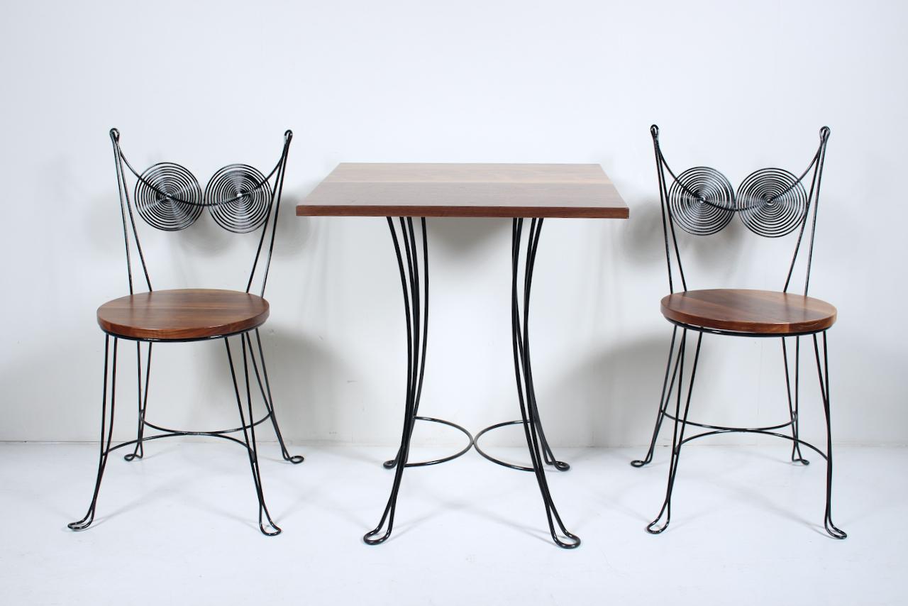 Tony Paul designed, Rubel produced, Black enameled Brass Wire & Walnut pair of dining chairs and table, 1954. Featuring sturdy, balanced, Black enameled Steel bent wire frameworks with double spiral Chair backs, replaced solid Black Walnut seats and