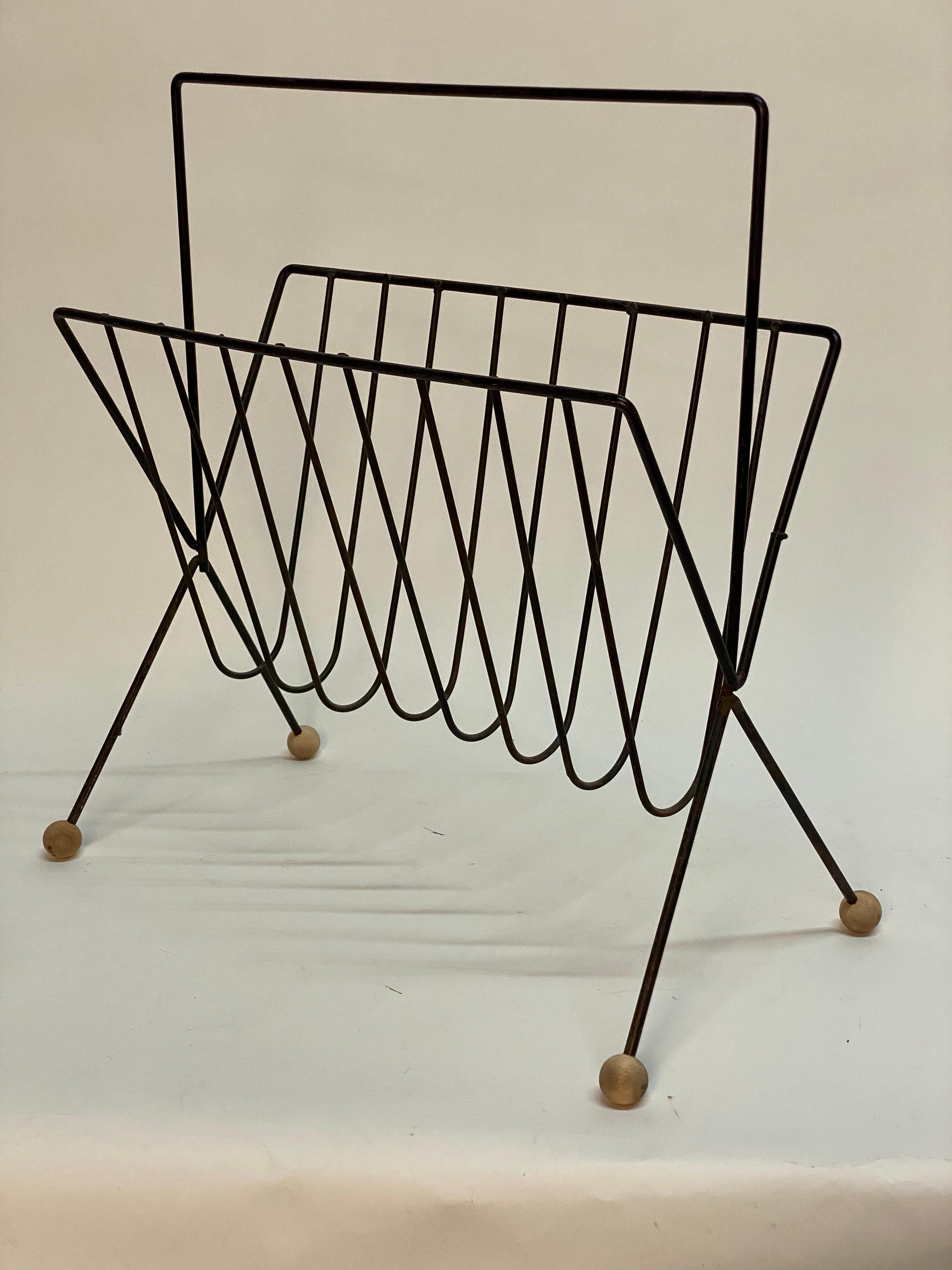 Bent iron with wood ball feet magazine rack designed by Tony Paul (1918-2010) for Woodlin-Hall. One of The United States top industrial designers. Designing everything from furniture to lighting for Westwood, Raymor, Robert Barber, Verplex,