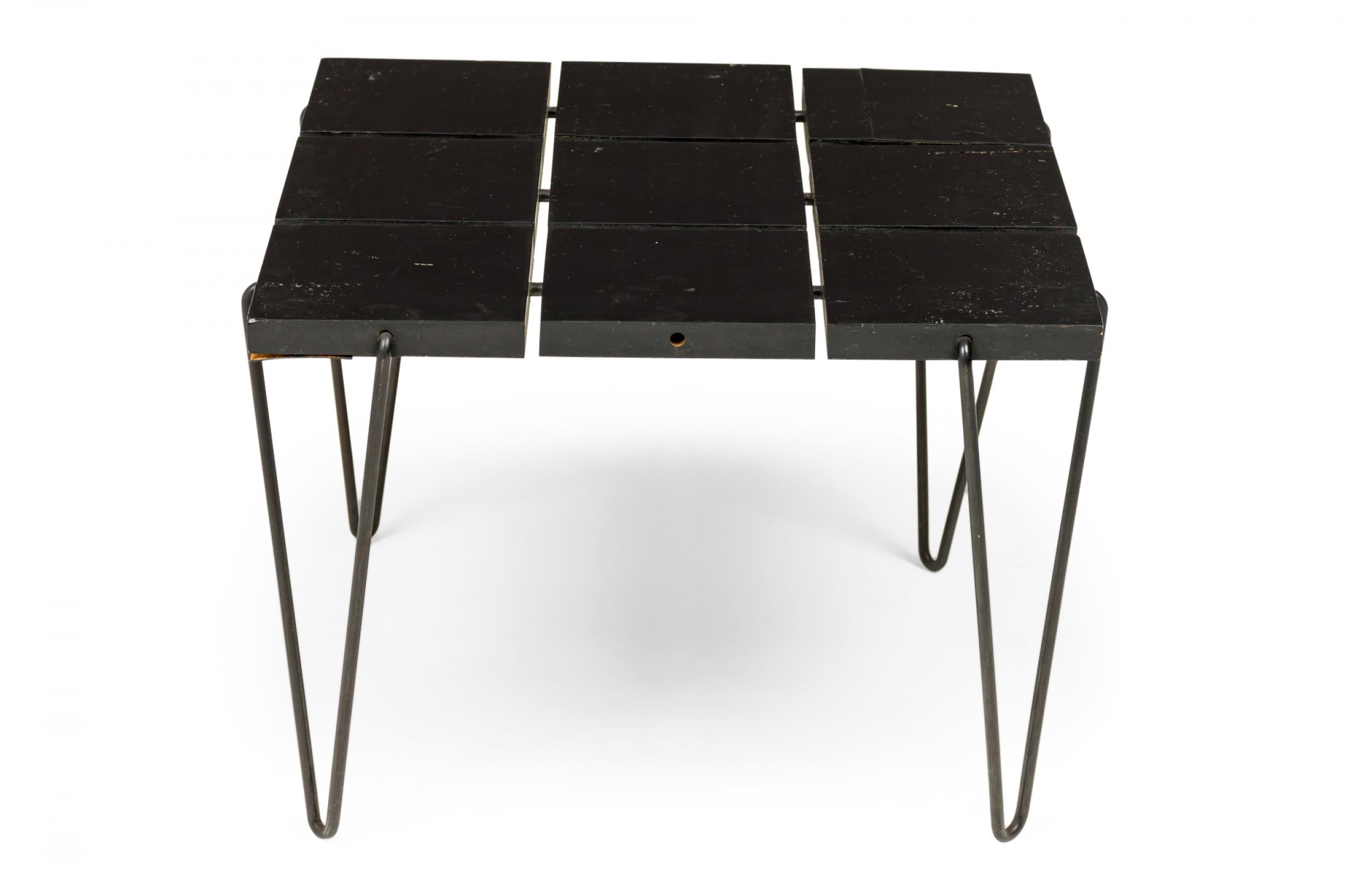 American Mid-Century end / side table with a top comprised of nine ebonized wooden square pieces connected by a flexible wire frame, resting on four black hairpin wire legs. (TONY PAUL)
