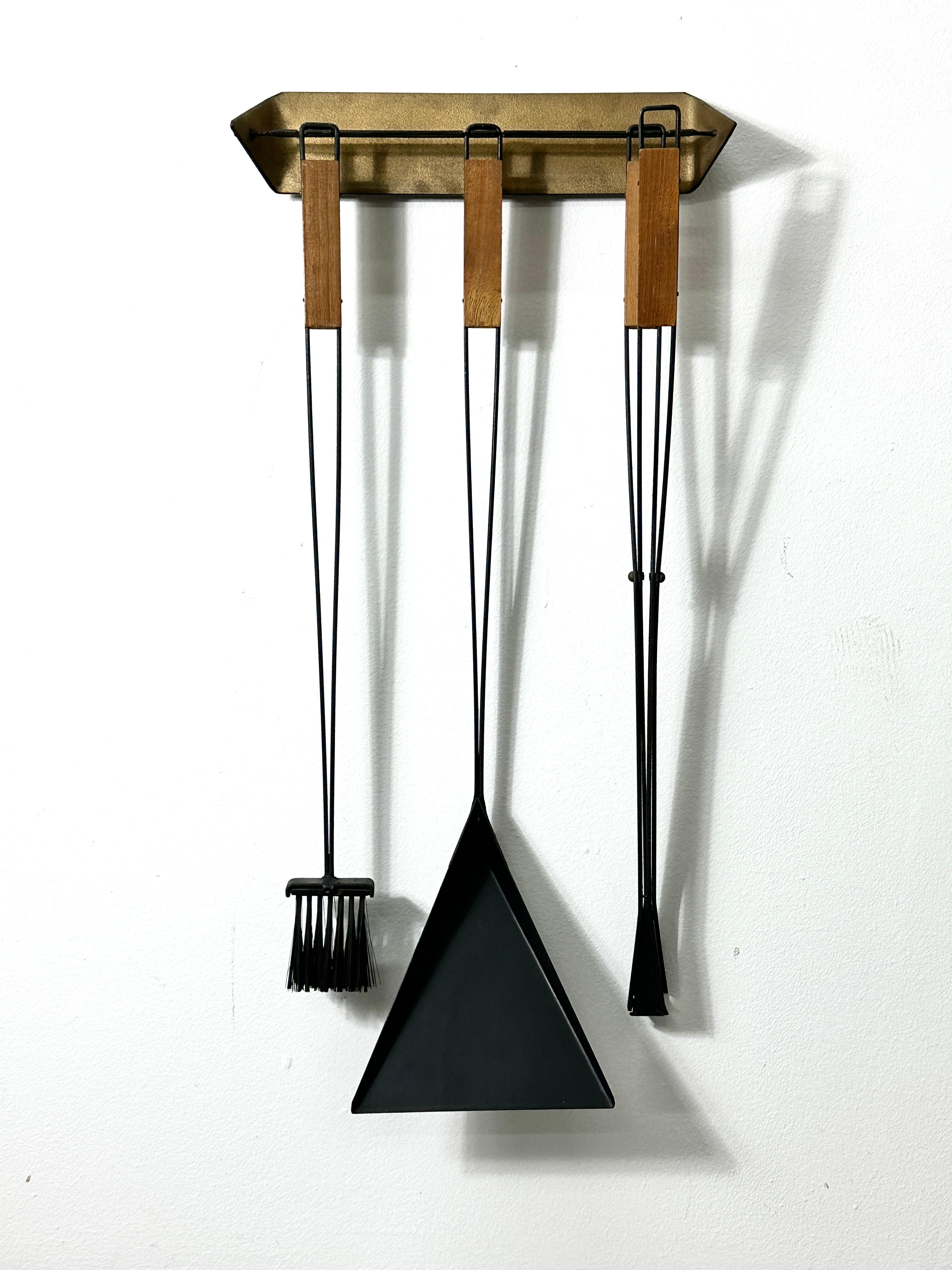 Rare wall mounted fire tool set designed by Tony Paul for Woodlin Hall circa 1950s
Black iron tools with gold edge detailing and wooden handles
Includes shovel wire brush and tongs with original wall bracket

Documented from the Fireset collection