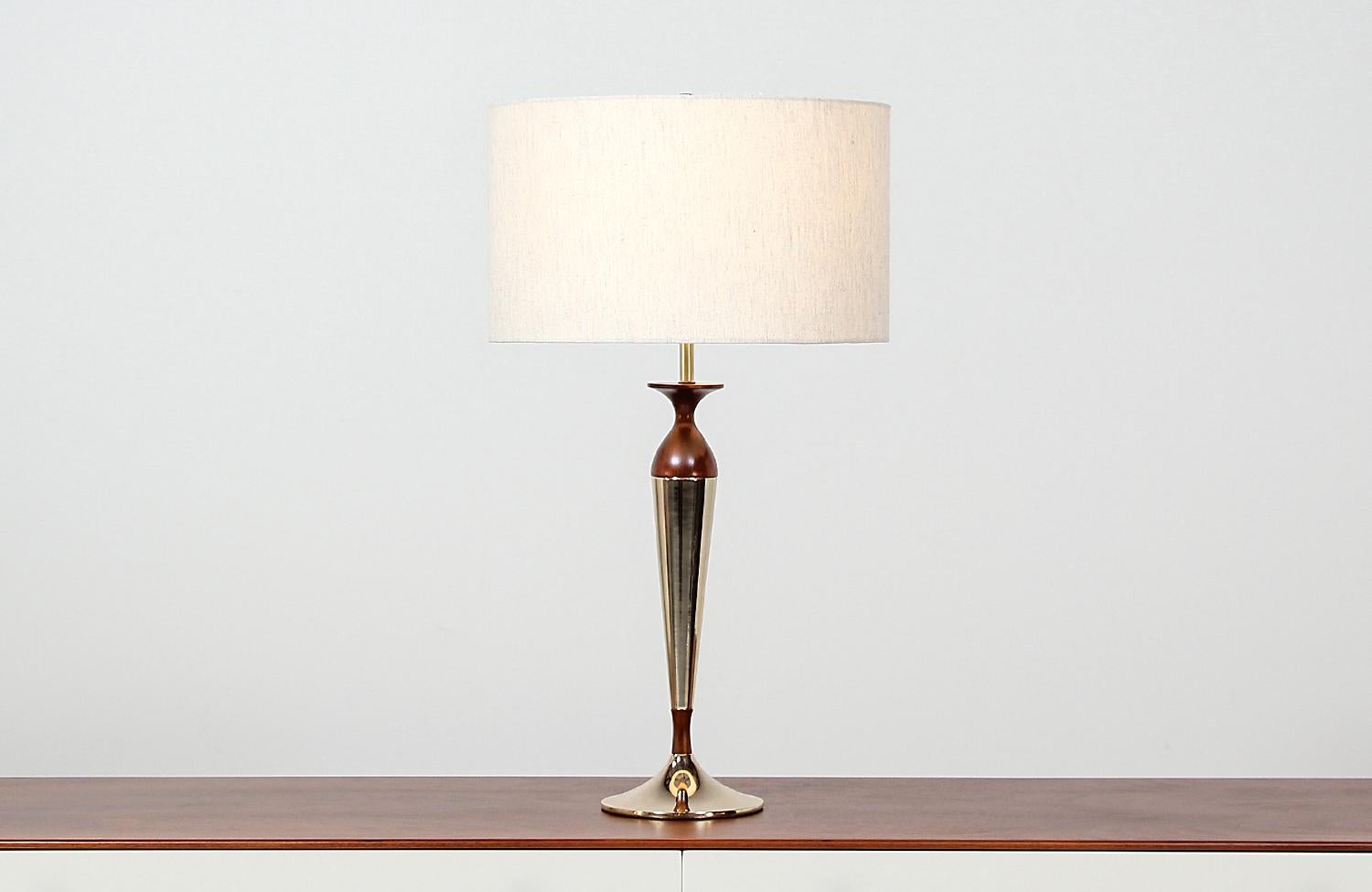 Dazzling table lamp designed by Tony Paul for Westwood Industries in the United States, circa 1950s. This stunning modern table lamp features a walnut wood body resembling the shape of an hourglass and is decorated with newly polished and re-plated
