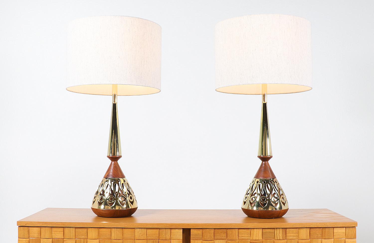 A stunning pair of table lamp designed by Tony Paul for Westwood Industries in the United States, circa 1950s. This dazzling set of table lamps features a richly-grained walnut wood body with newly polished brass details on the base and top of the