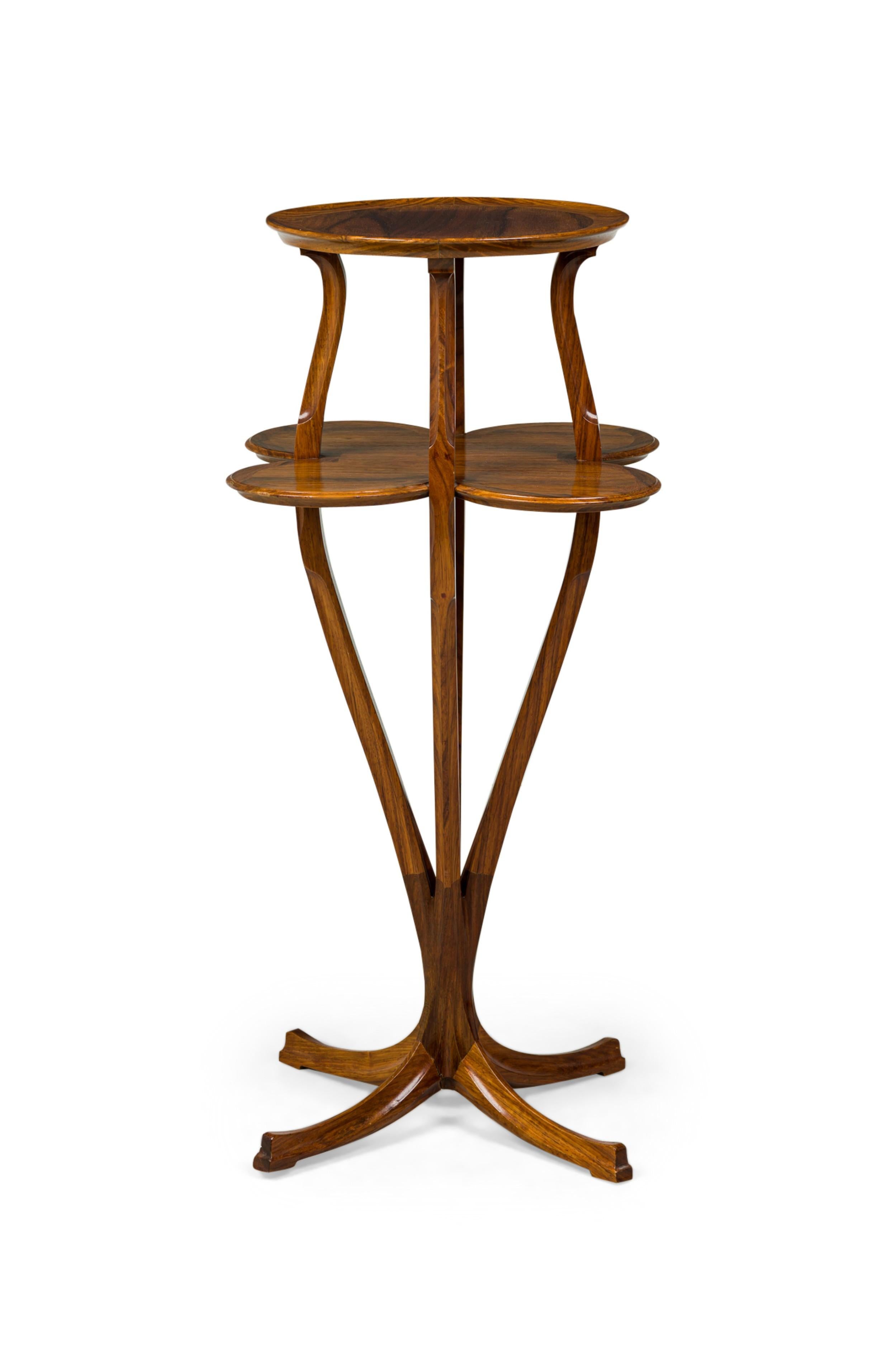 French Art Nouveau two-tier pedestal table with a lower shelf in a clover shape supporting a circular upper tier, connected by carved supports and resting on a carved 4 leg pedestal base. (TONY SELMERSHEIM)
