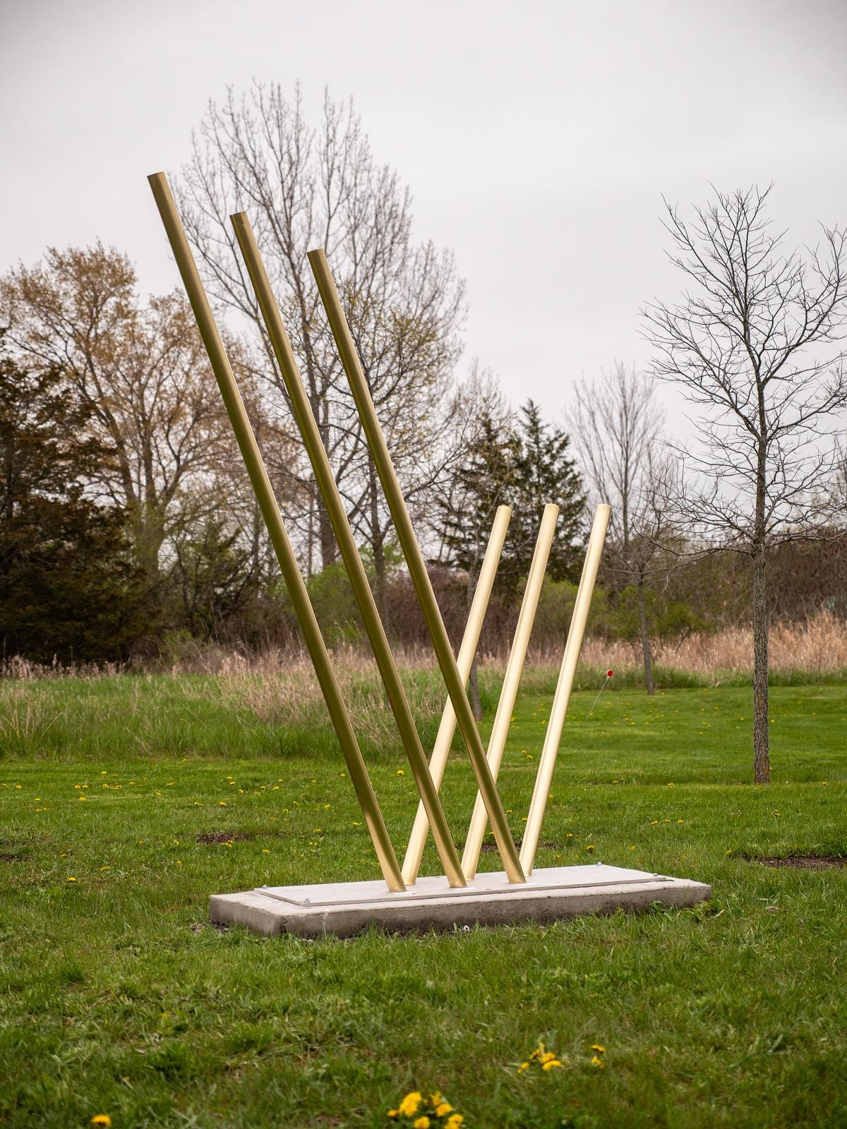 Solid steel rods coated in brilliant brass appear to rise out of the earth and reach for the sky in this dramatic sculpture by Canadian artist, Tonya Hart. 

Hart creates work that is inspired by forces of nature—light, energy and magnetism. 

“As a