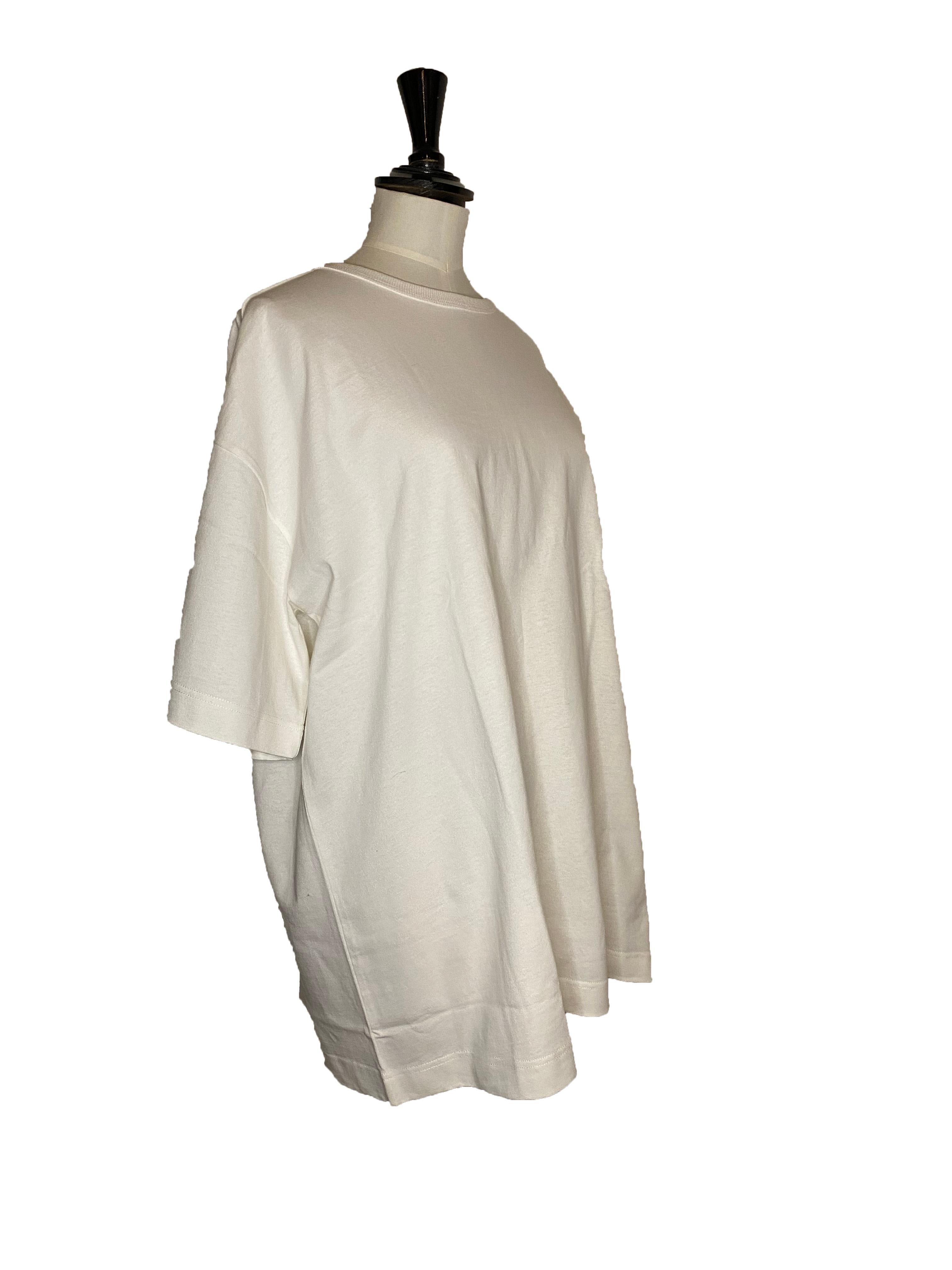 Maglietta unisex in cotone grezzo di Toogood. Collo rotondo a coste con maniche corte.  Vestibilità oversize con spalla scesa e maniche generose che arrivano appena sopra il gomito. Taglia media. Colore del marchio: Gesso. Prodotto in Portogallo.