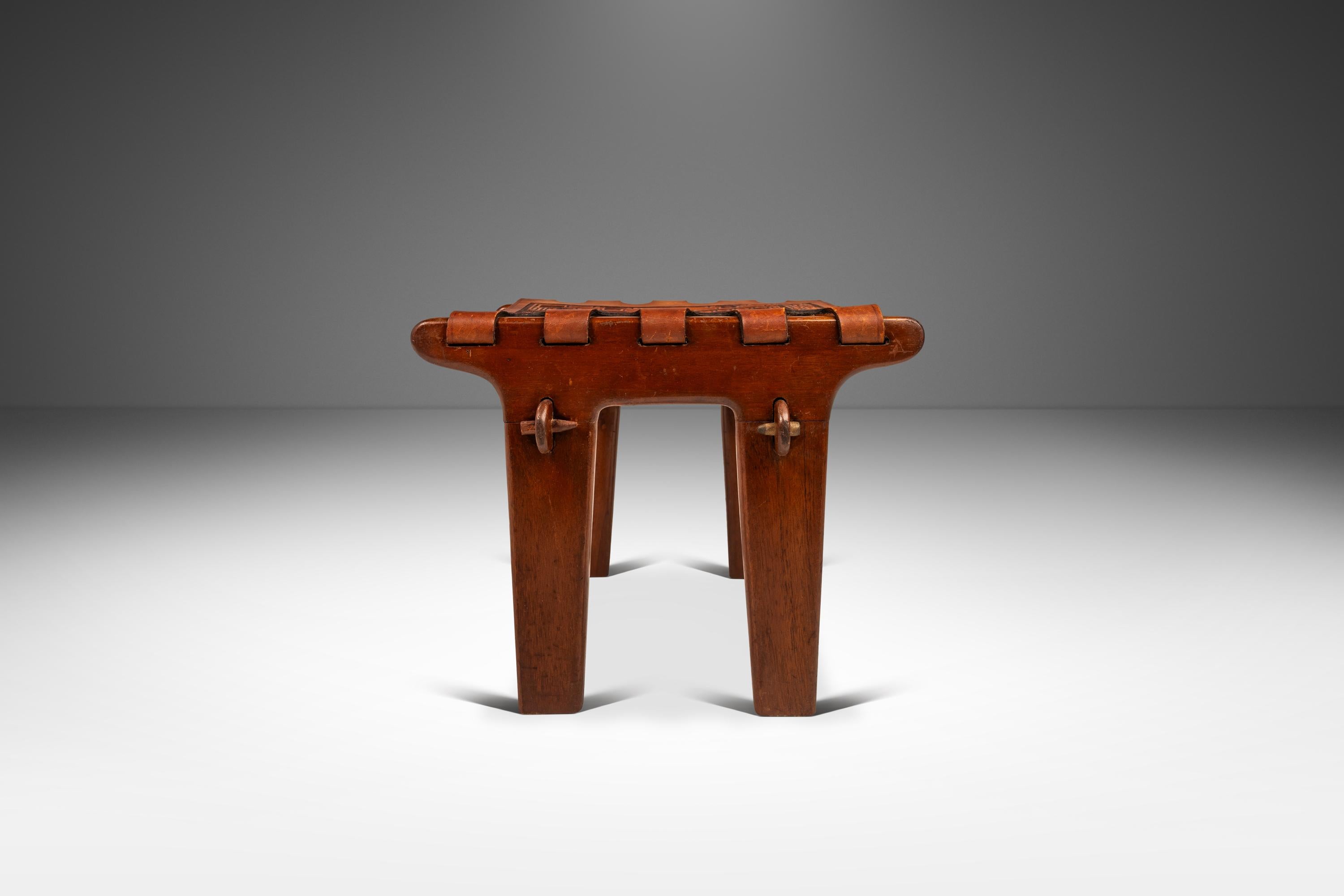 Voici un rare tabouret à bretelles de l'incomparable Angel Pazmino. En état d'origine, vintage. Le cadre, sculpté dans du bois de jacaranda massif, présente une patine qui ajoute du caractère à une pièce déjà riche.  L'écharpe, composée d'une peau