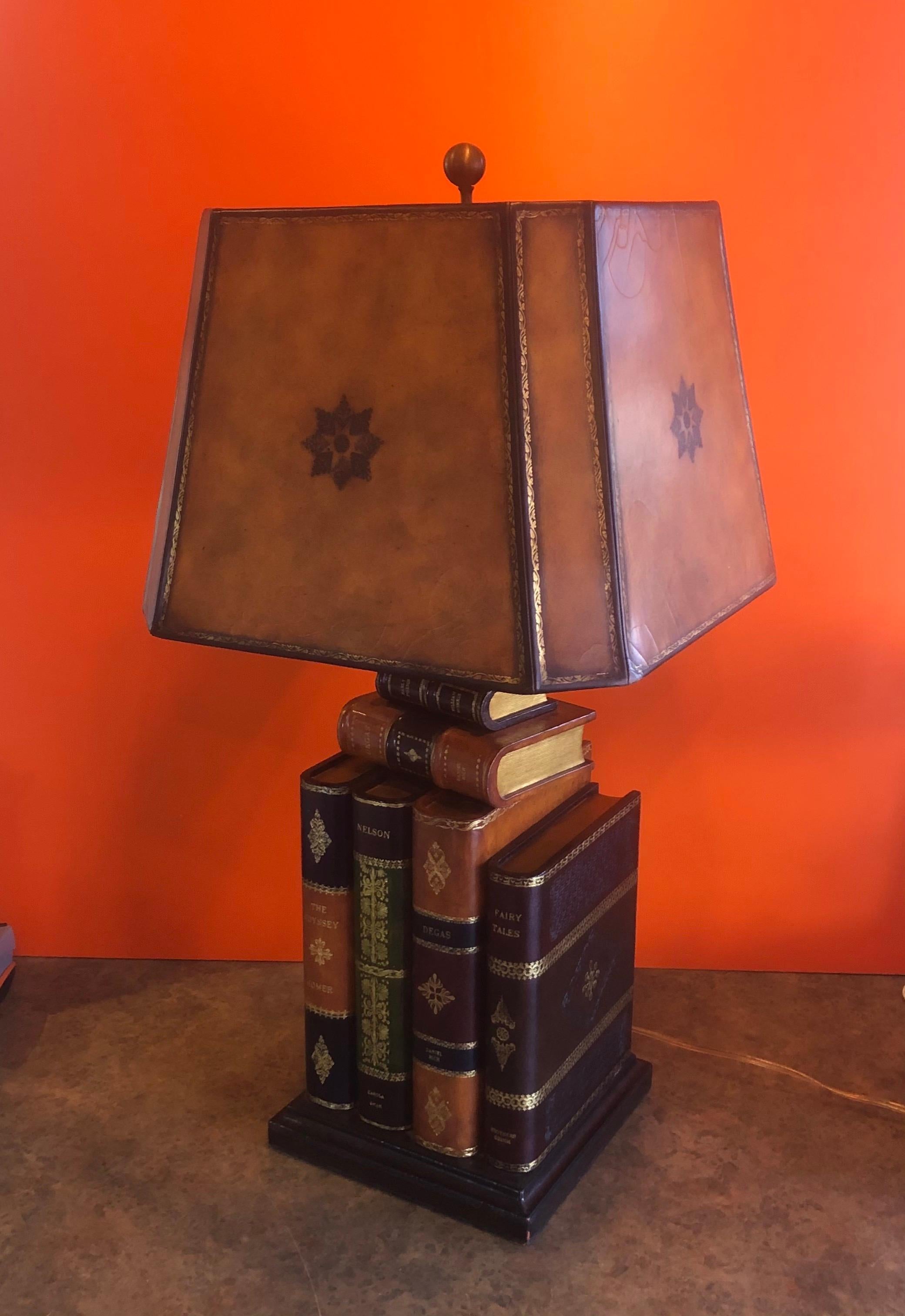 Tooled leather faux books table lamp by Maitland Smith, circa 1990s. The lamp is very heavy and extremely well made and comes with the original embossed leather lamp shade. The lamp has a tree-way brass socket and measures 16.5