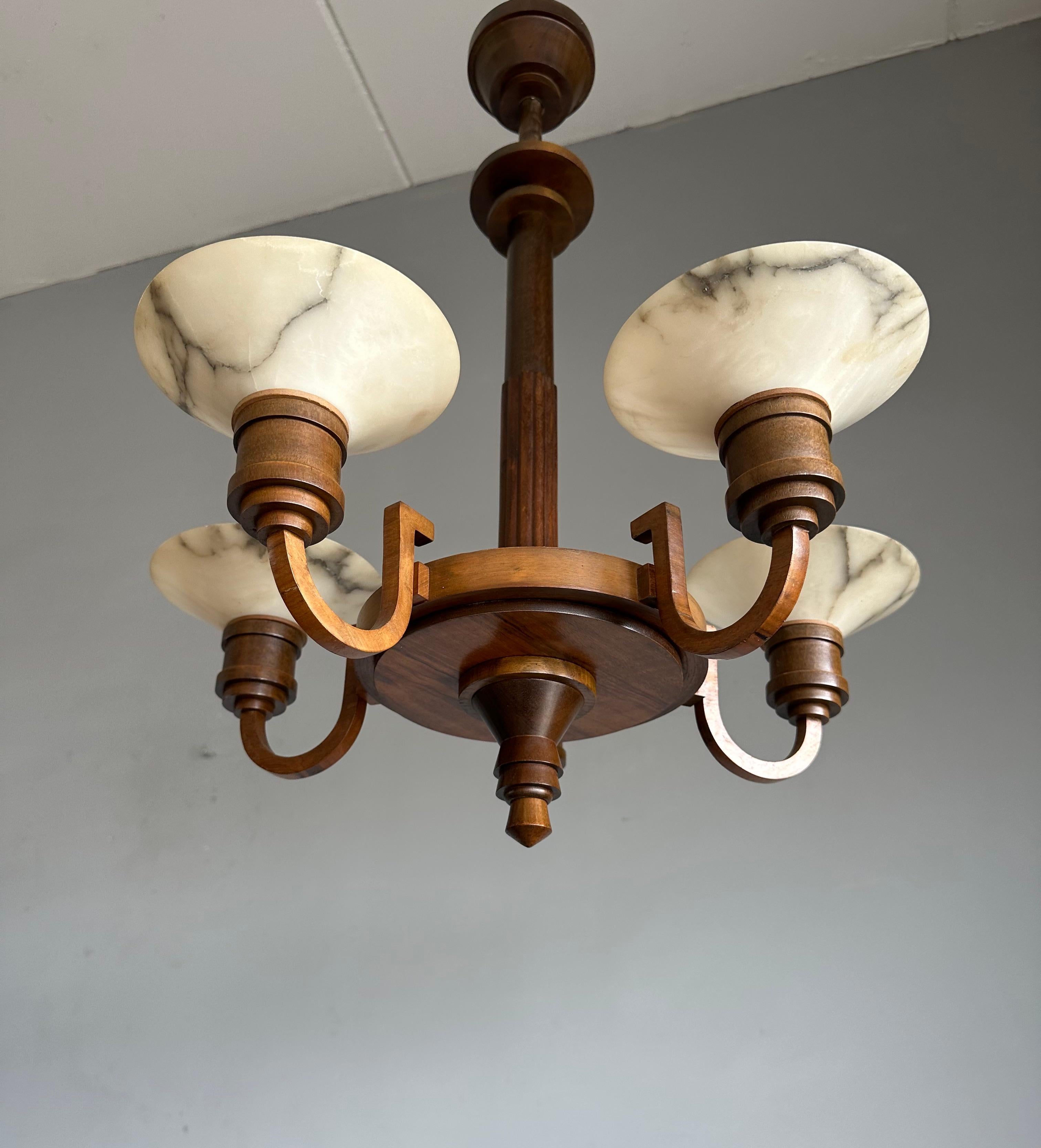 This also unique and good size, eye pleasing Art Deco chandelier, stands out for several reasons:

Firstly, it has a stunning nutwood 'body' which is in excellent condition. 
Secondly, its perfect Art Deco design makes it a true joy to own and to