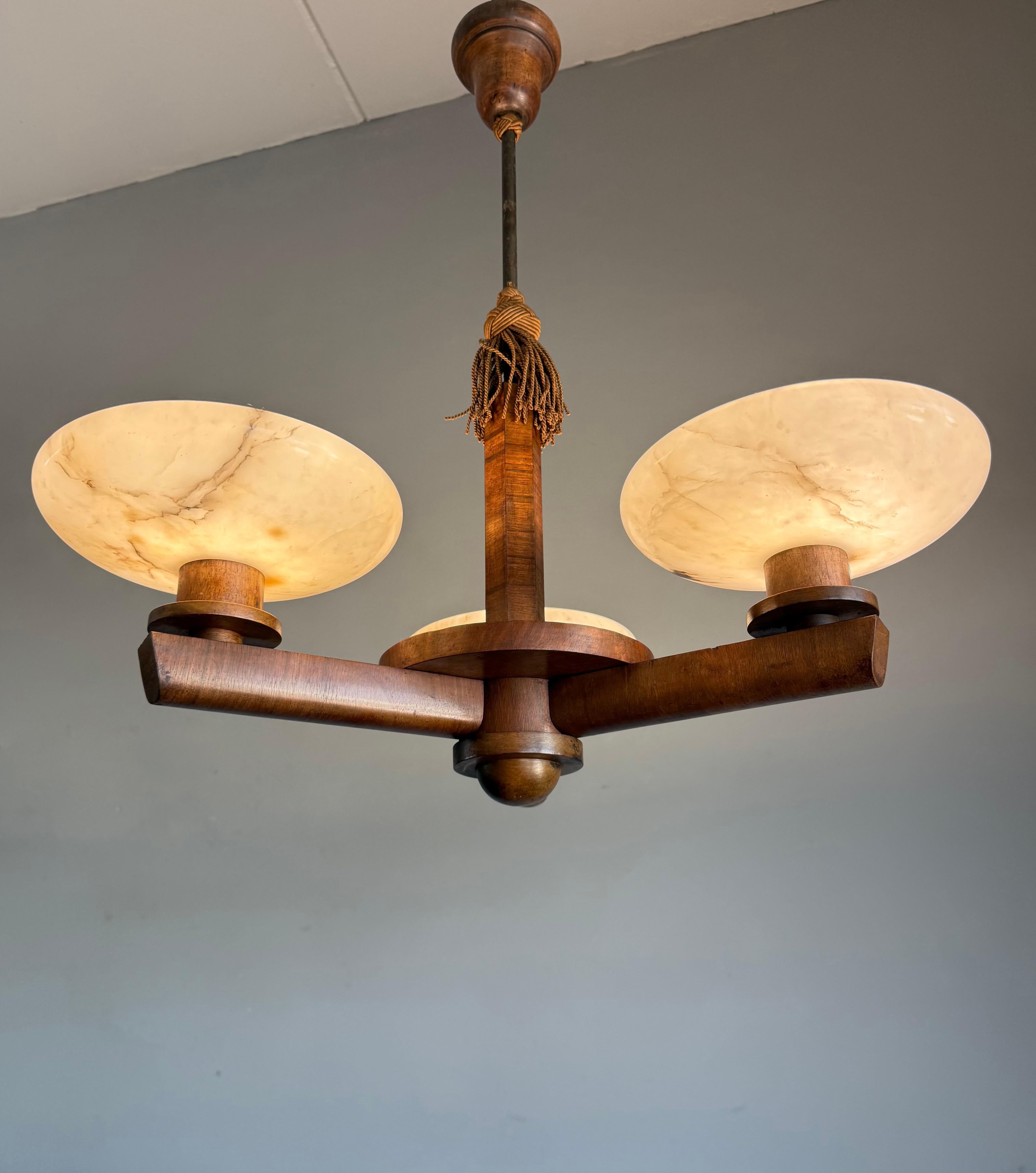 This also unique and good size, eye pleasing Art Deco chandelier, stands out for several reasons:

Firstly, it has a stunning nutwood veneer body, which is in good condition.

Secondly, its perfect Art Deco design makes it a true joy to own and to