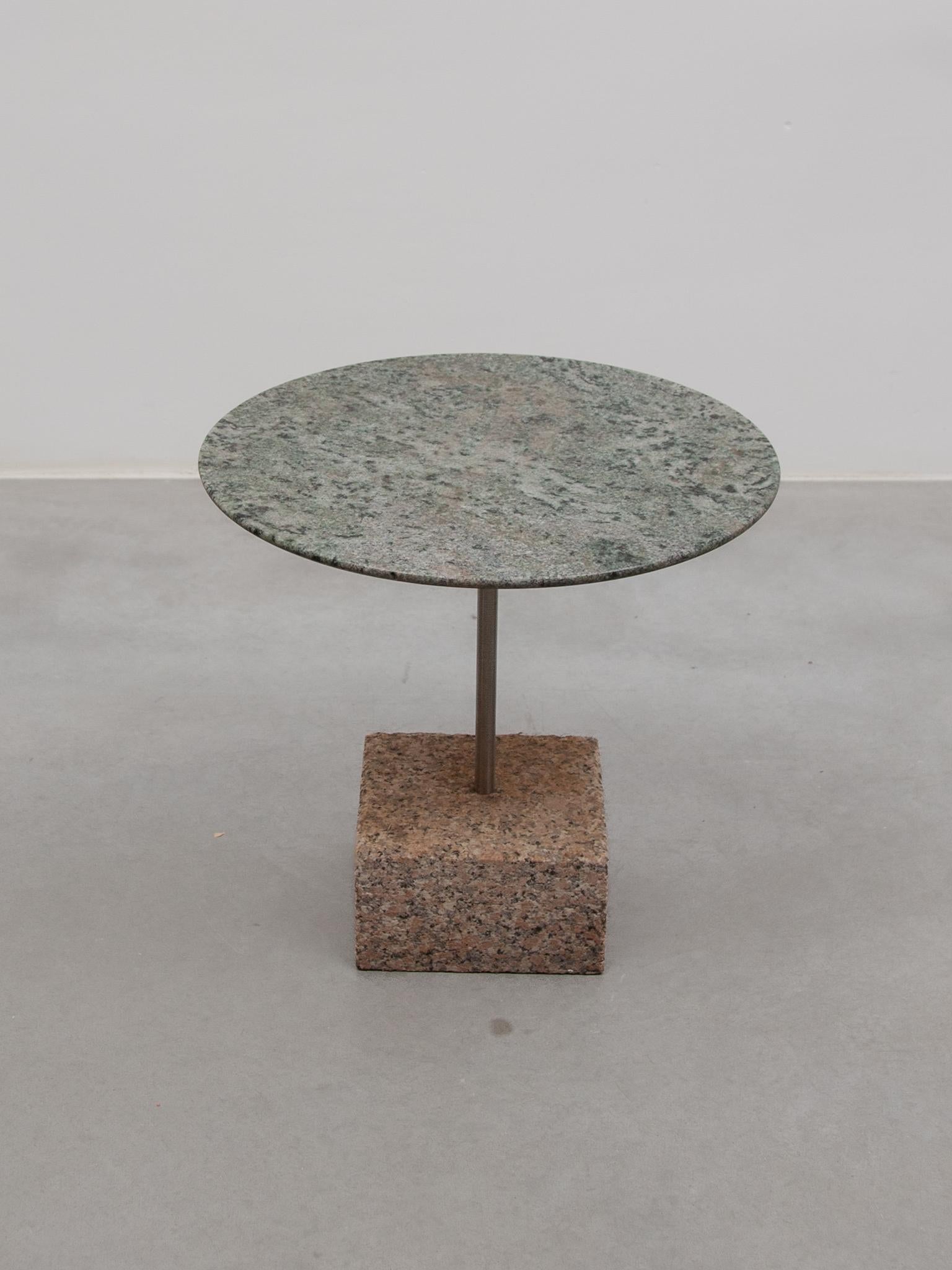 A beautiful brutalist small side table with a natural stone top in veined green and a grey-stone marble base.