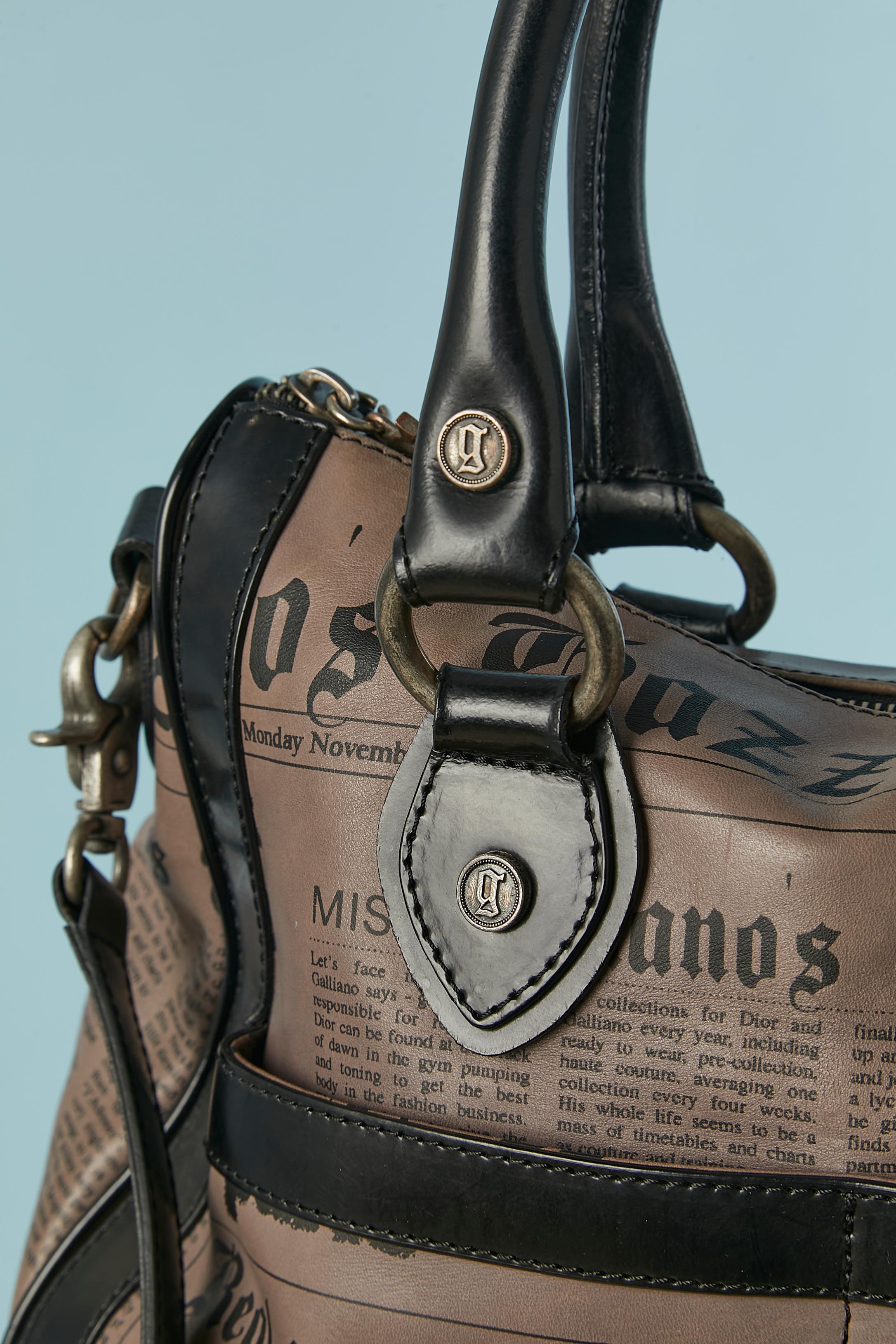 Borsa in pelle con manico superiore e stampa Newspaper. Fodera in poliestere con marchio. Chiusura con zip in alto al centro. 2 tasche esterne. 4 tasche interne (una con zip, 3 senza) 
DIMENSIONI: 32CM X 30CM X 14CM 
Lunghezza del manico: 53 cm (X 2