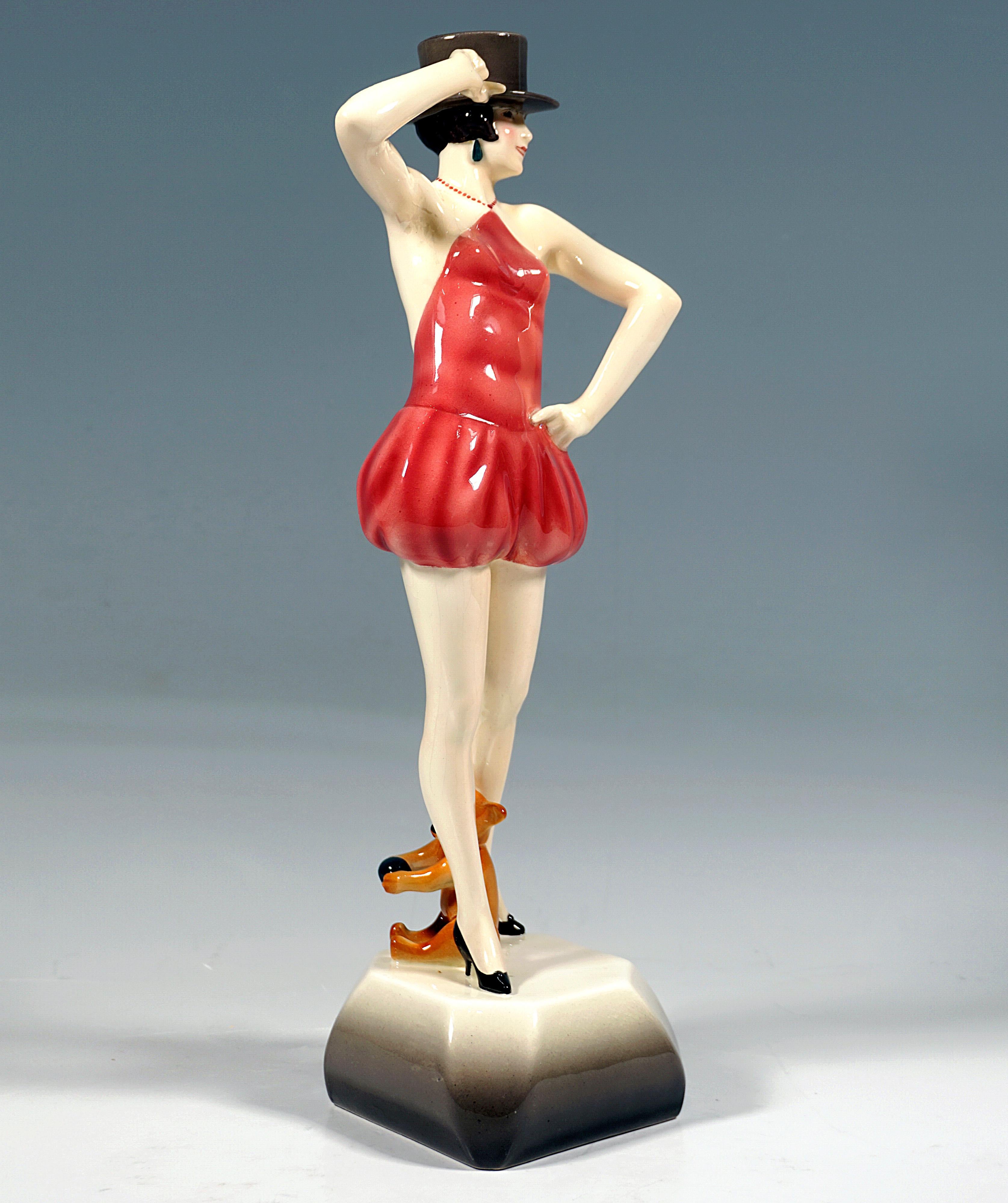 Very rare Viennese ceramic figure from the late 1920s:
Young, fancy dancer in a tight costume with a shoulderless and backless top held by a pearl necklace and short harem pants, black heels on the feet, posing with a dark grey-brown top hat on her
