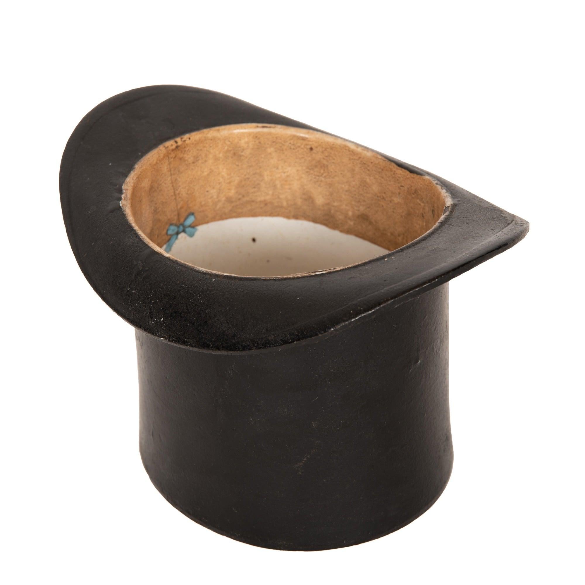 Un'insolita e splendida sputacchiera in ferro patinato a forma di cappello a cilindro da gentiluomo.