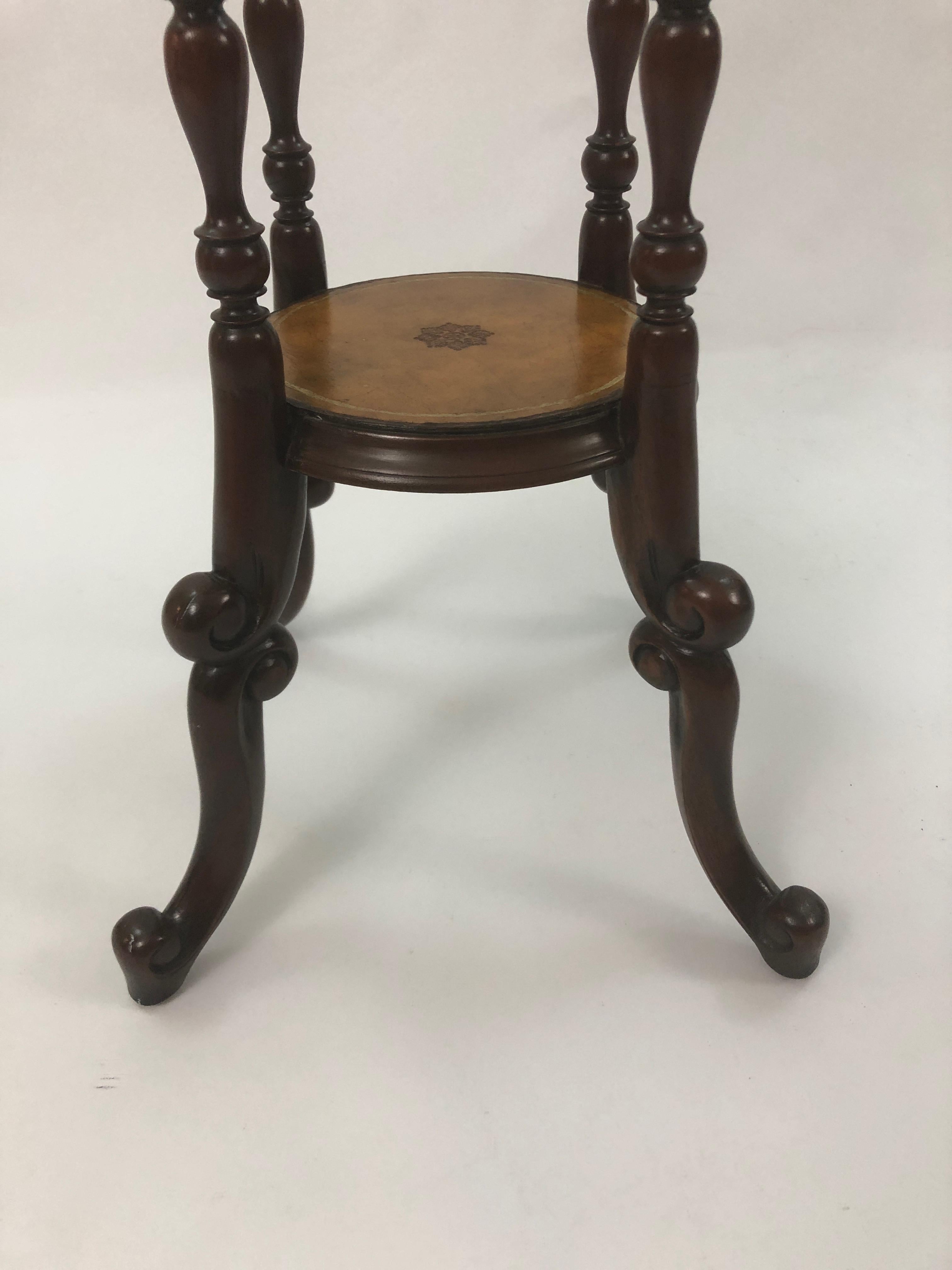 A handsome tall mahogany stand having barley twist structure and tooled leather on both circular surfaces with central decorative emblem indicative of Maitland Smith creations.