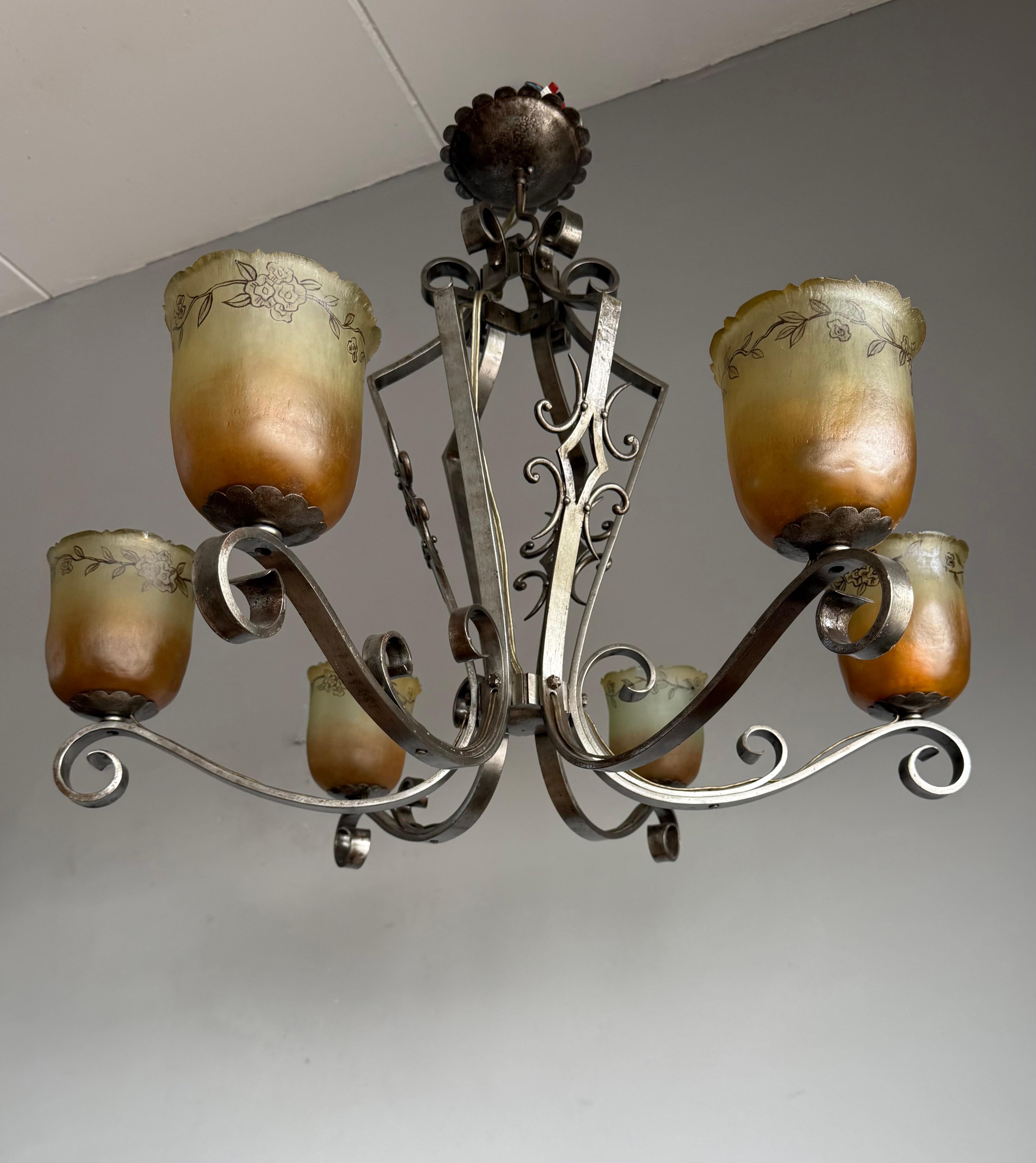 A beautifully crafted wrought iron chandelier, brought to life by the delicate charm of its glass shades, each one a unique, hand-blown work of art.
