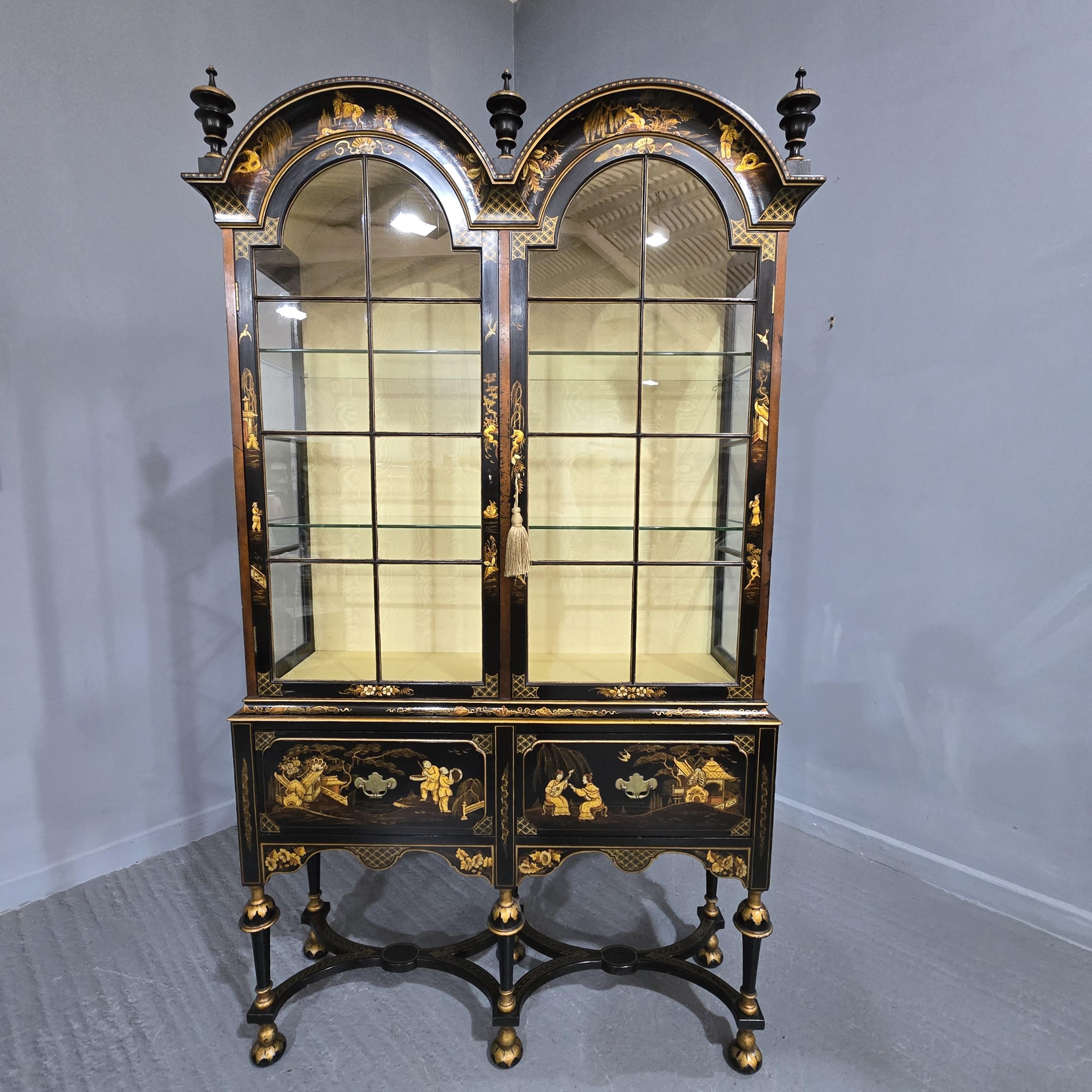 An outstanding black double dombed chinoiserie laquered oriental style display cabinet on two drawer base, lemon watered silk interior, two doors with two plate glass shelves, lovely shaped stretcher, comes into two peices for transport, in