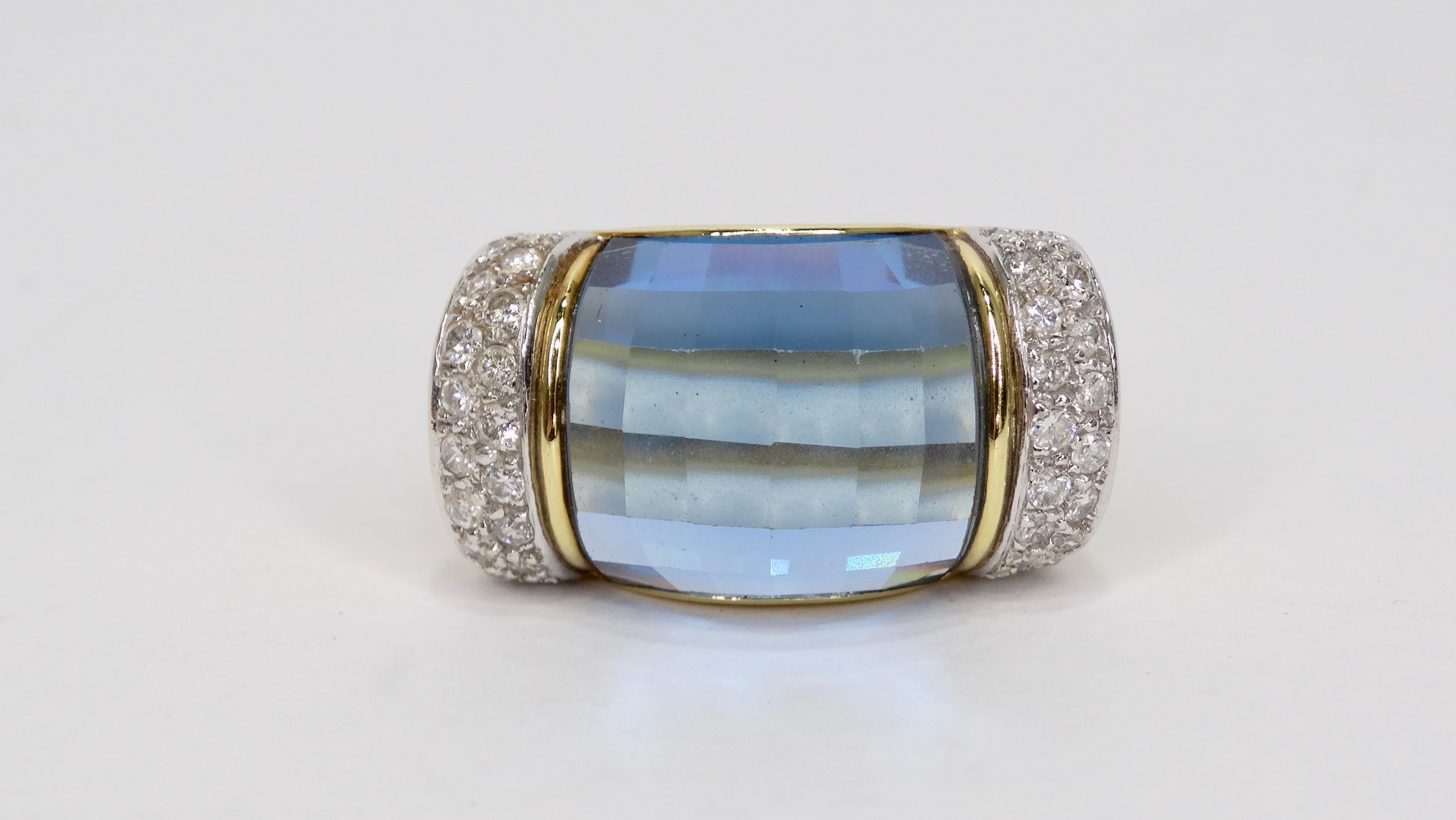 Complete your evening look with this gorgeous ring! Circa mid-20th century, this 18k gold ring features a think band with a beautiful blue topaz gemstone in the center and 4 total rows of brilliant cut diamonds on the side. Stamped 750/18k, is a