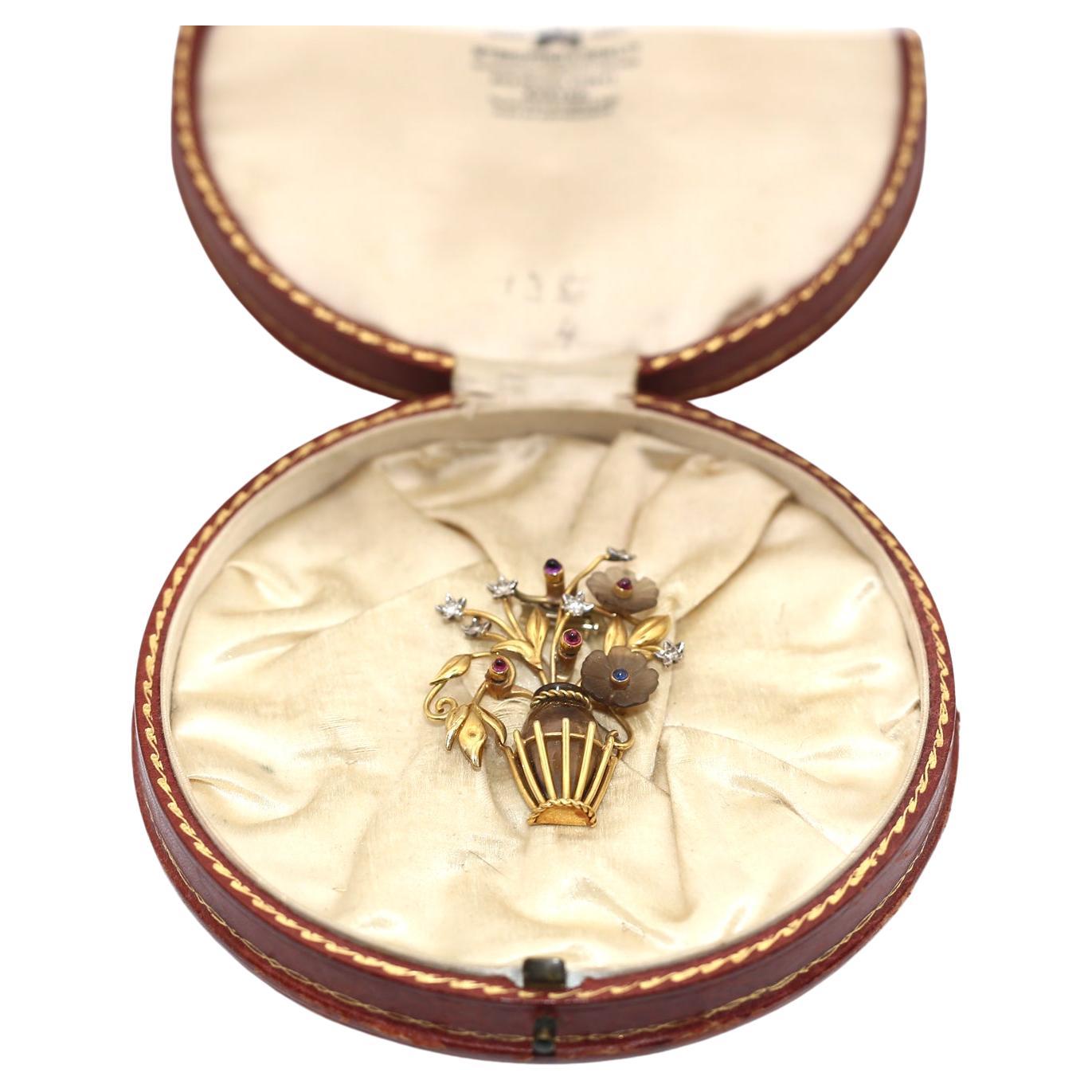 Vintage brooch depicting a basket (vase) holding a bouquet of flowers set with fine precious stones. Diamonds, cabochon Rubies & Sapphires.
The vase is made of fine transparent Topaz of a huge size. The level of the craftsmanship is just of the