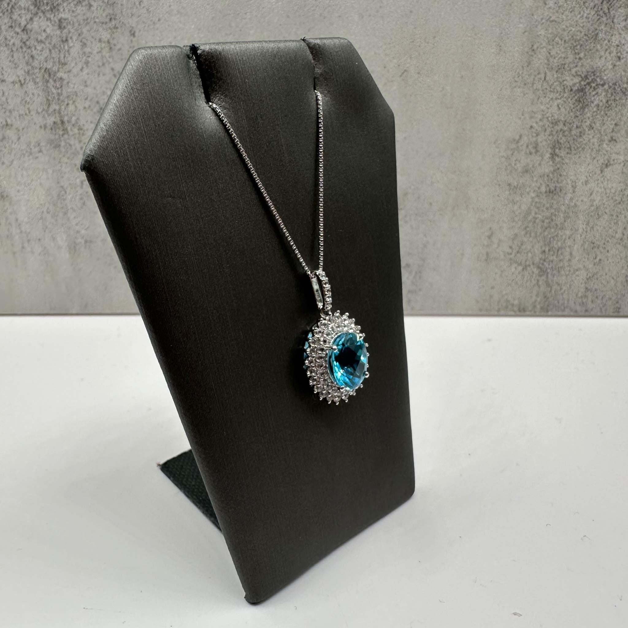 This elegant Topaz Necklace in sterling silver features a 10x8mm oval blue topaz, complemented by approximately 0.40ctw of round white topaz, creating a stunning contrast of colors. The necklace is 18 inches in length, making it perfect for layering