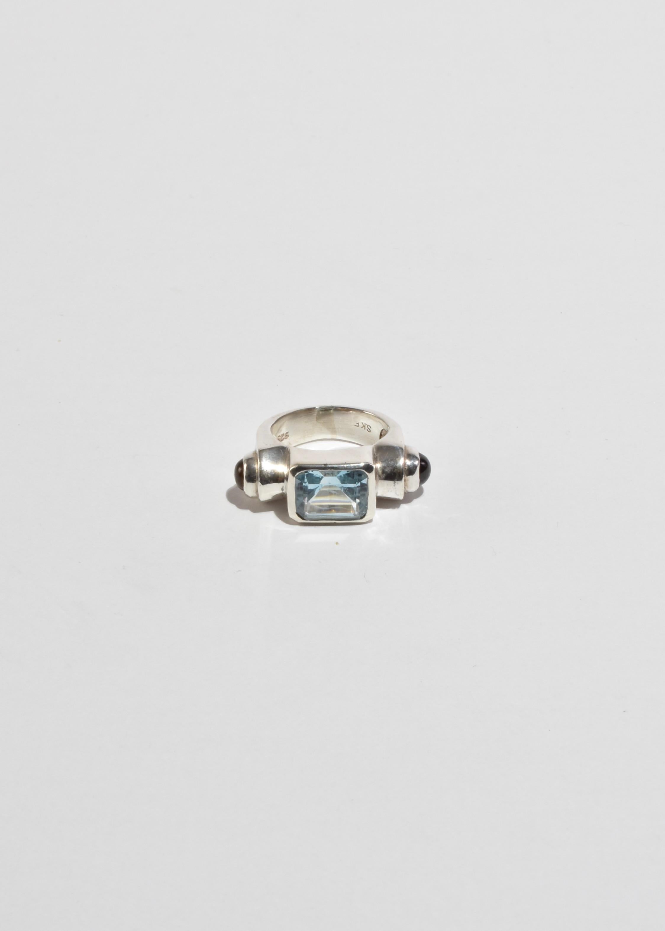 Stunning, vintage sterling ring with a faceted blue topaz stone and round ruby and citrine cabochon detail. Stamped SKE 925.

Material: Sterling silver, ruby, topaz, citrine.