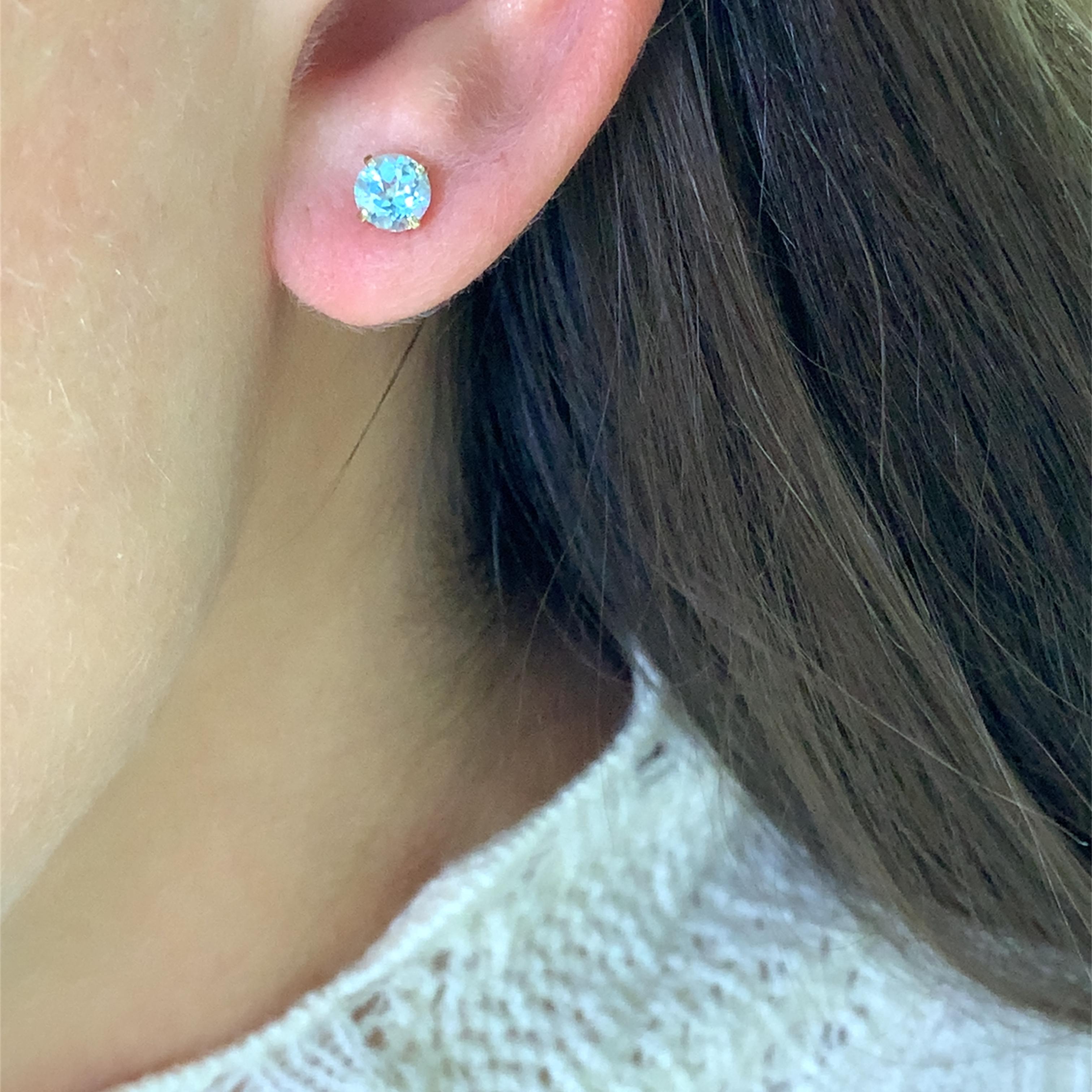 Scopri l'eleganza senza tempo di questi splendidi orecchini con gemme blu topazio. Realizzati con precisione in oro giallo 9ct, ogni orecchino presenta un taglio rotondo che cattura e riflette magnificamente la luce blu, rendendoli l'accessorio