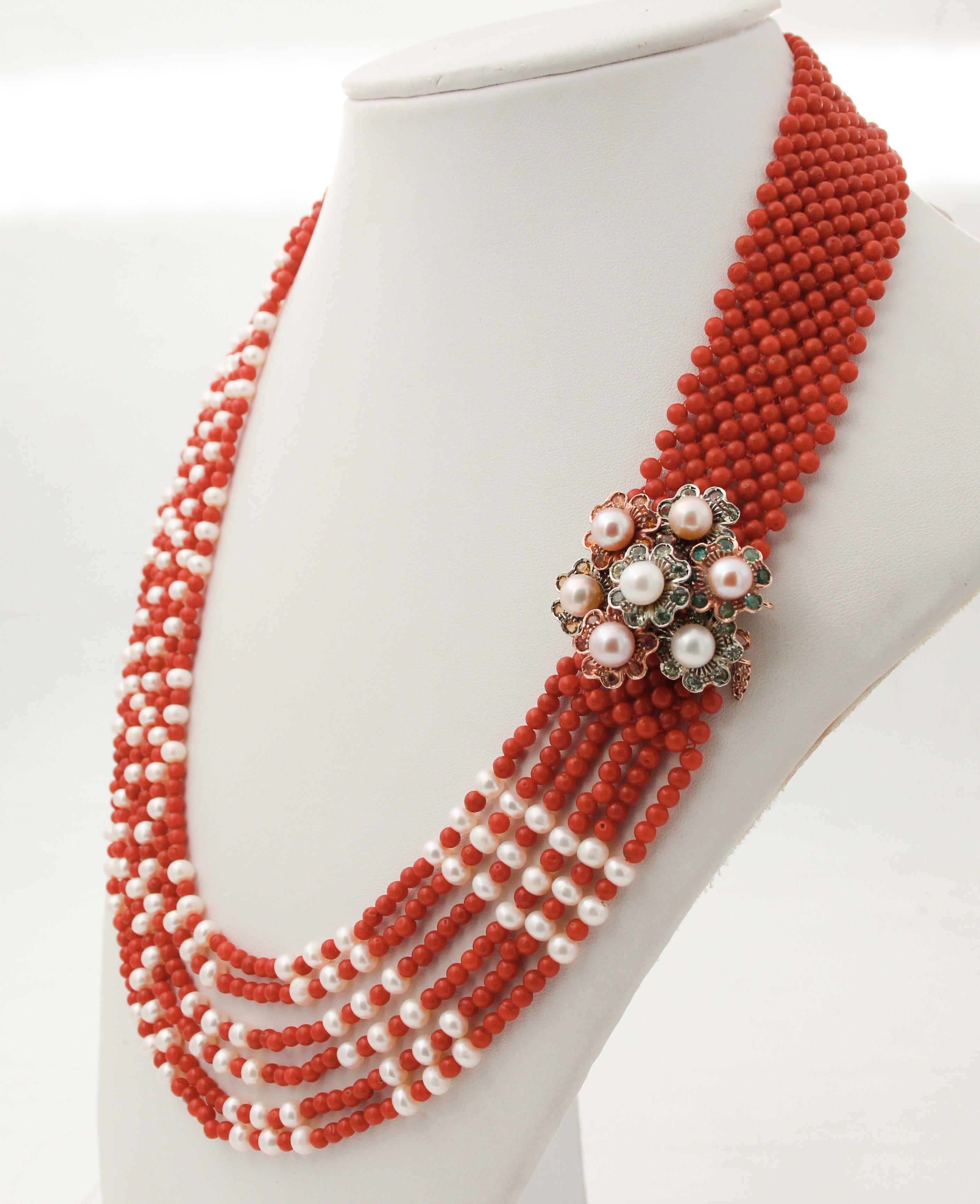 Beautiful multi-strands necklace composed of a  closure with little flowers in 9 karat rose gold and silver studded with emeralds, topazs, sapphires and pearls.
It is completed with strands of corals and pearls.
This necklace is totally handmade by