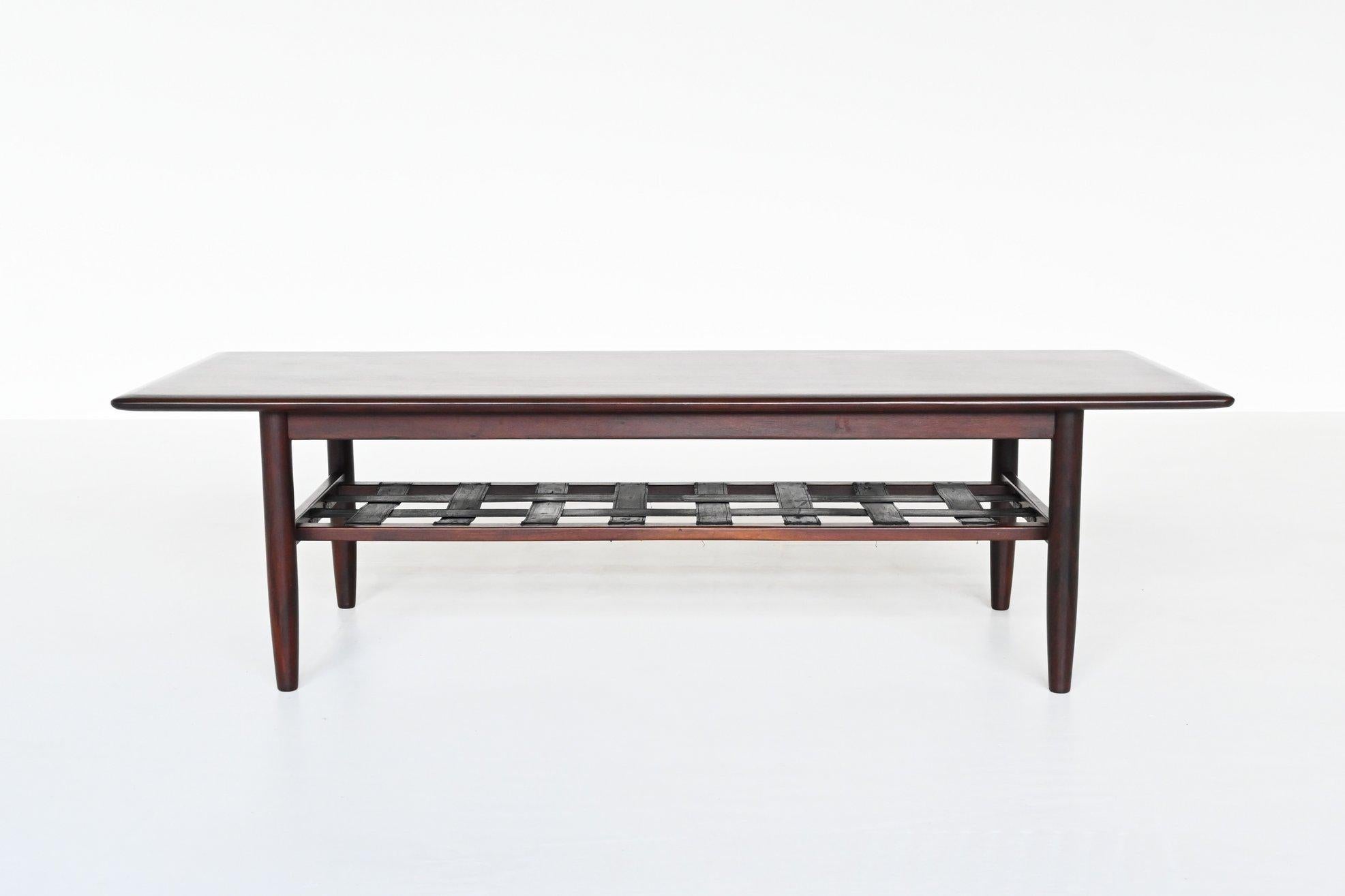 Beautiful coffee table manufactured by Topform, The Netherlands 1960. This high quality rosewood coffee table has solid legs and a veneered top with a leather strap magazine rack as second storage level. It is long, stable and quite heavy. This