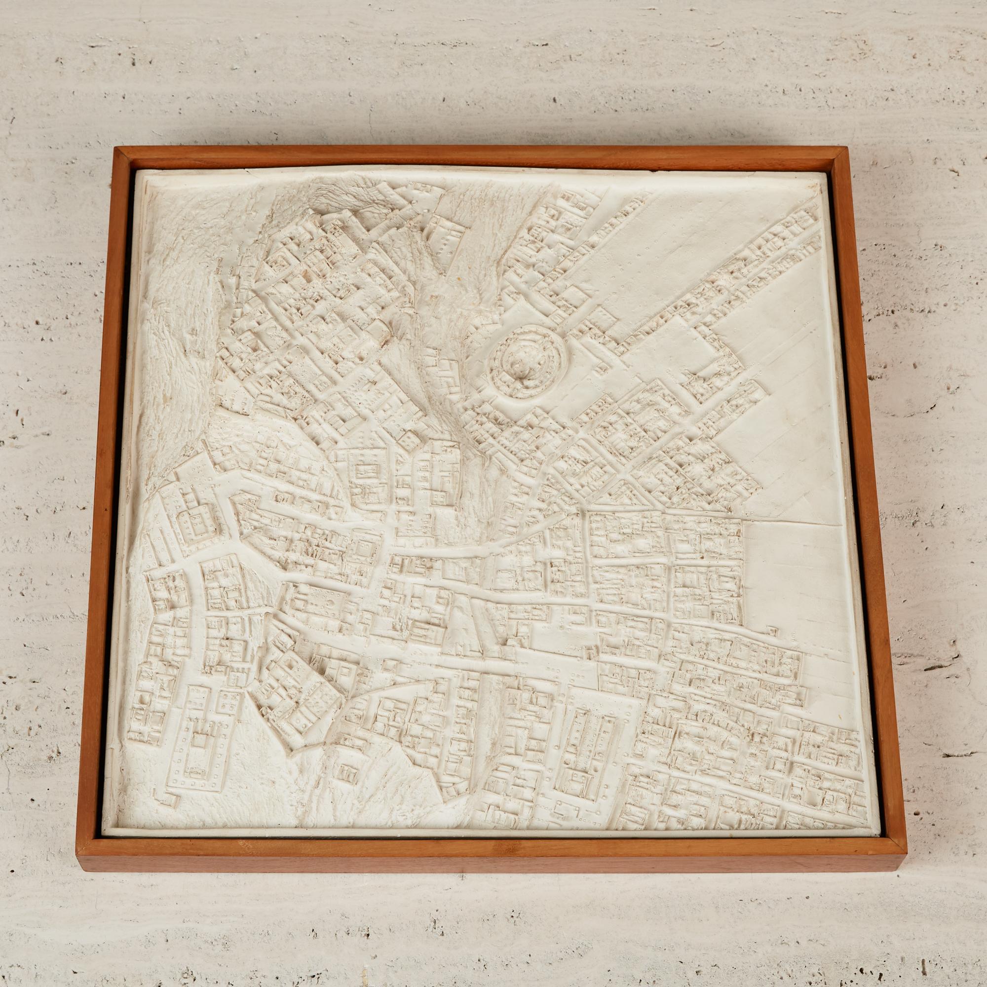Made from glazed ceramic, this wall art is like a topographic map of a village with a small colosseum from the time of the Roman Empire. Though chances are more likely that it is something that the artist conjured up with his mind rather than