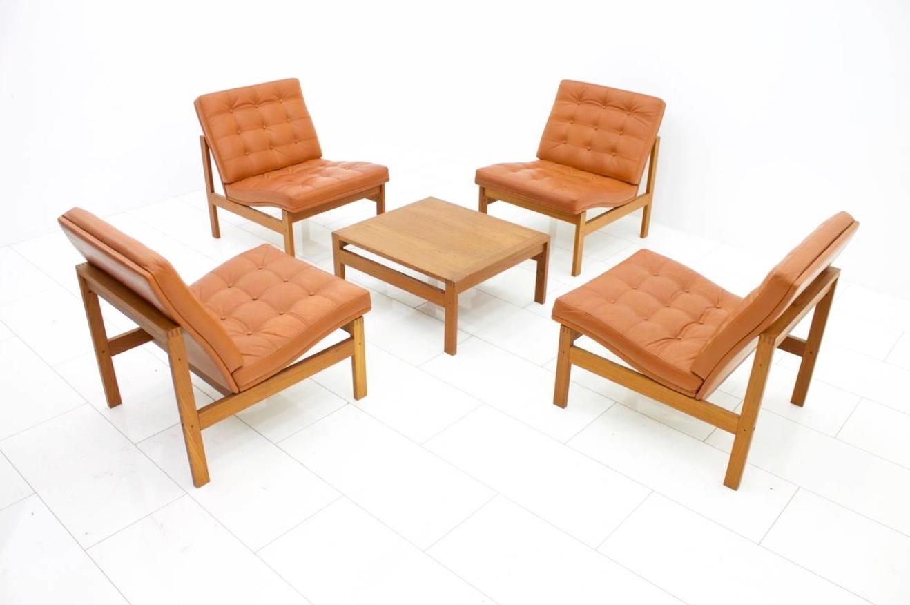 Set of four lounge chairs and a Side Table.
Solid teak wood and cognac brown leather by Torben Lind and Ole Gjerlov-Knudsen for France & Sons Denmark, 1962. 
Very good original condition.

