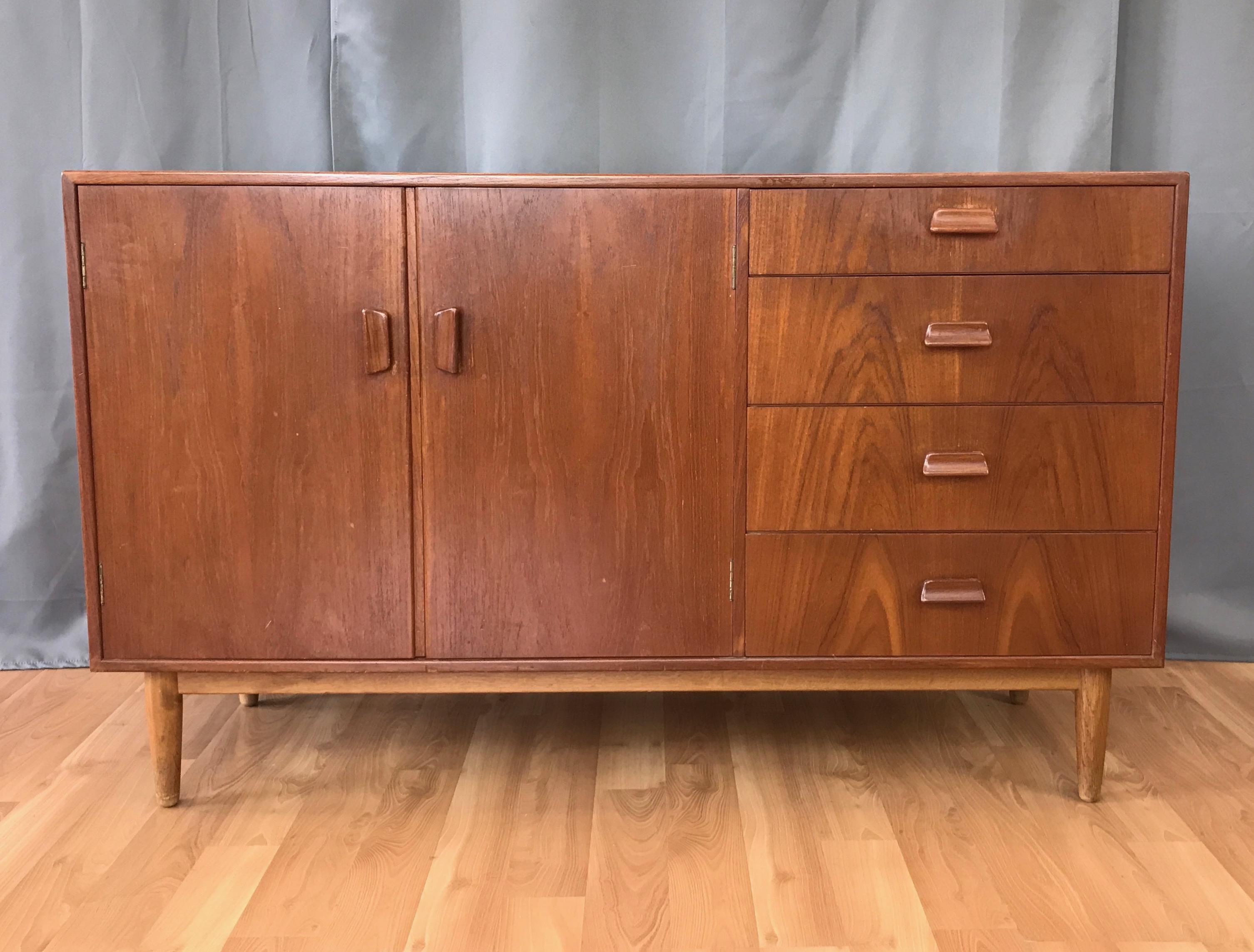 A 1960s Danish teak and white oak sideboard by Torben Strandgaard for Falster Møbelfabrik.

Finished on all sides in nicely figured bookmatched teak. Two-door cabinet with pine interior and a pair of adjustable height shelves. Four drawers, the