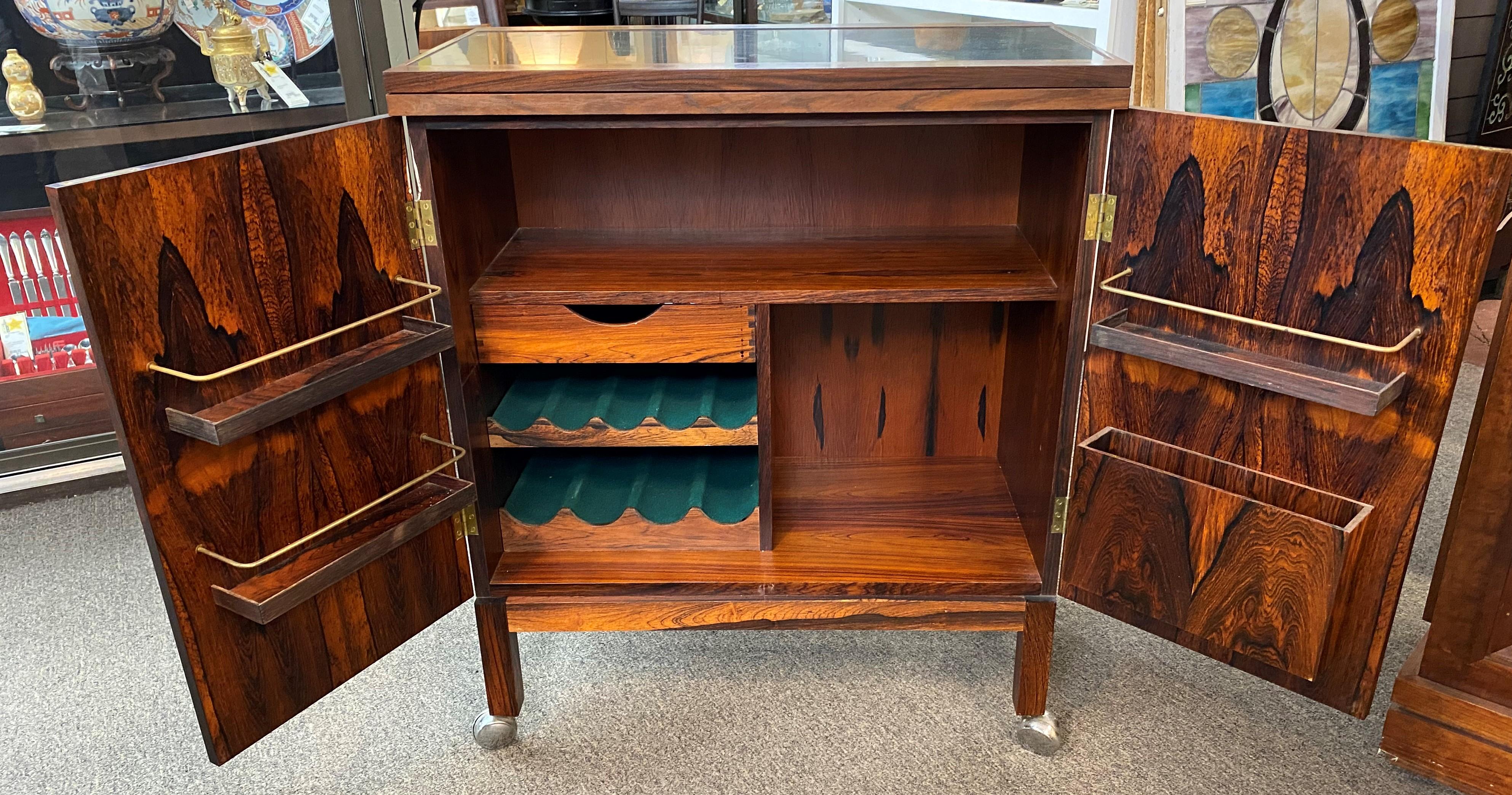A fine Mid-Century Modern “flip top” rosewood, bar cabinet/ cart by Torbjorn Afdal for Mellemstrands Trevareindustri / Bruksbo Modell of Norway, featuring richly grained rosewood, with a fully finished back and rosewood interior. The finished back