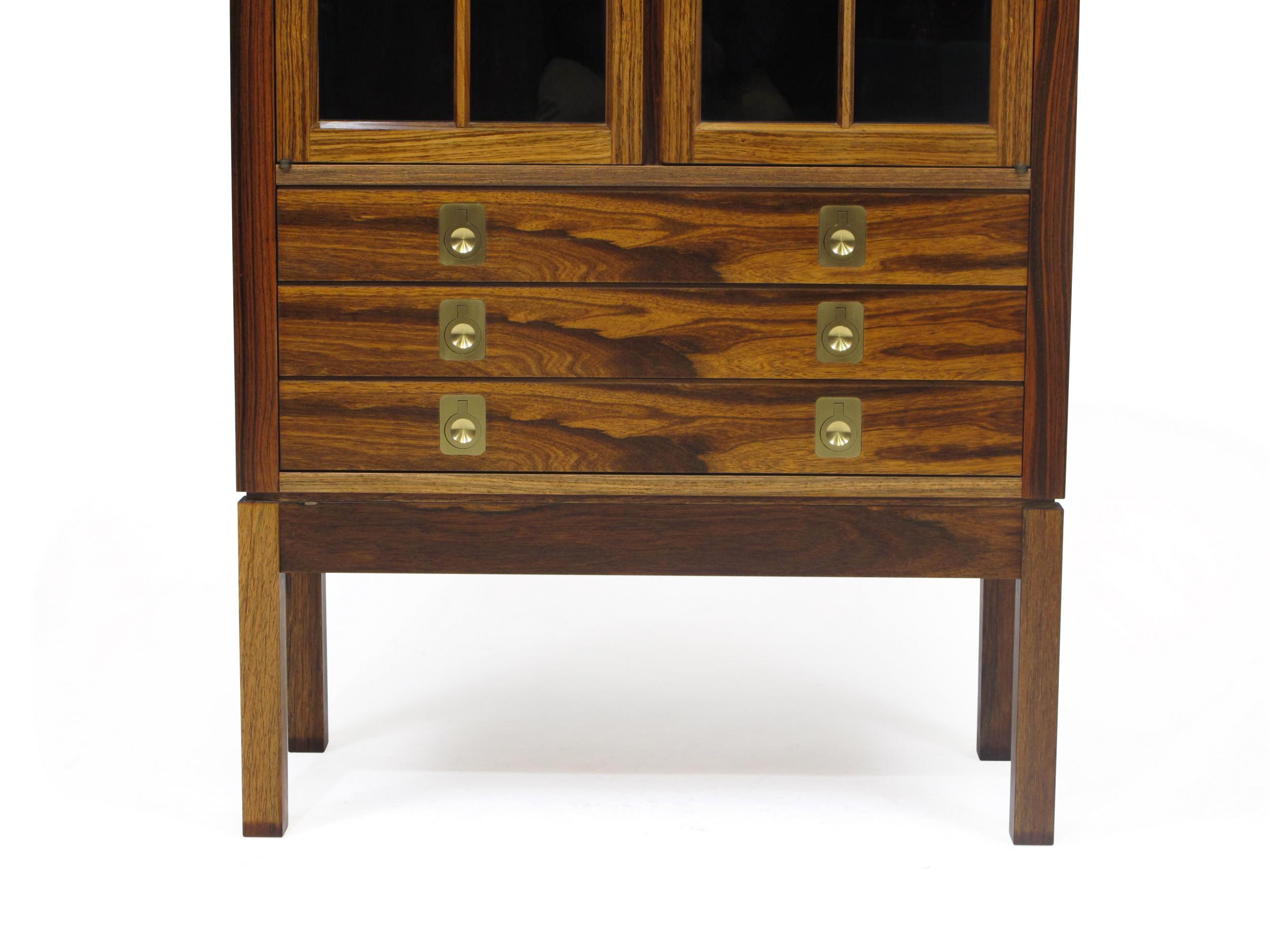 Rosewood china cabinet designed by Torbjorn Afdal for Mellemstrand Moblefabrik, circa 1960 Norway. Features a three-drawer cabinet with brass pulls and a locking glass hutch. Rosewood pattern match down the front of drawers with brass handles. Glass
