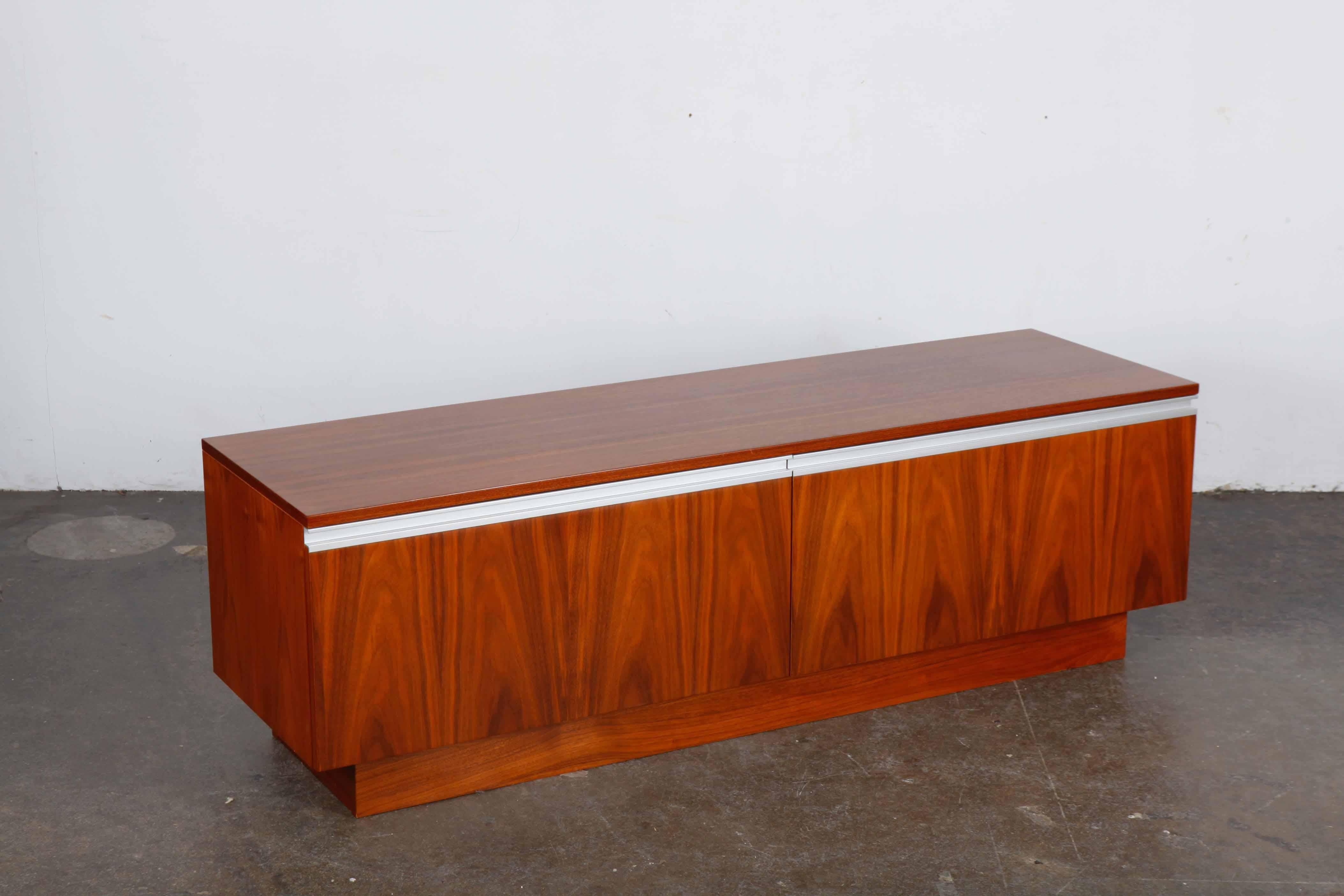 Low Norwegian sideboard in rosewood with metal accents on a plinth base, designed by Torbjørn Afdal for Bruksbo. It has two drop front doors with ideal storage for vinyl and audio and electronics equipment. Newly refinished in satin lacquer.