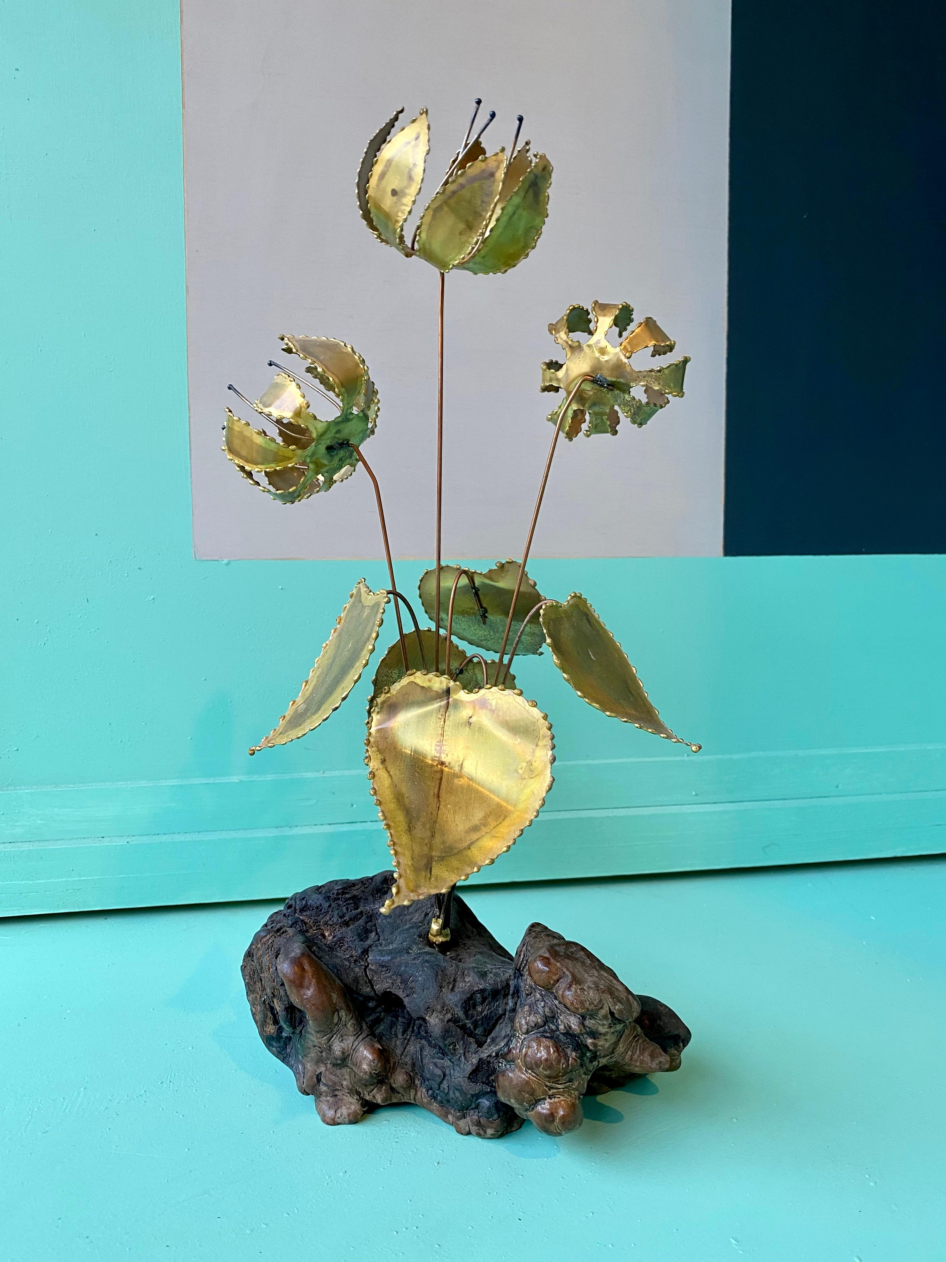 Torch-cut brass sculpture of lillies, mounted on a burlwood base, by Gerd Scharrelmann. This elegant sculpture has a delightful kinetic effect. The flowers and stems shiver, producing a delicate rustling sound when disturbed by movement or a breeze.