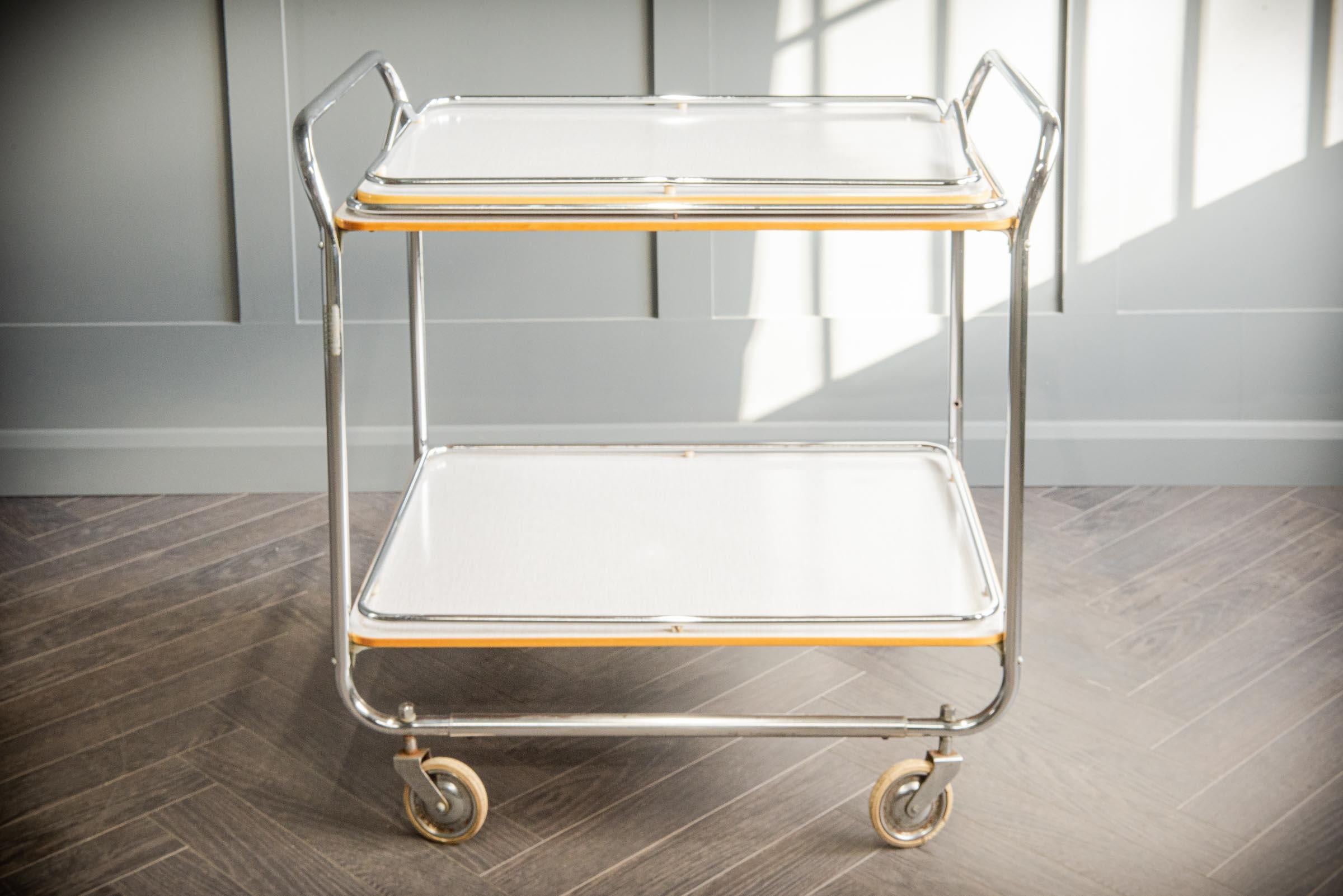 Art Deco cart designed by Torck. Designed as a drinks trolley. Comes with a removable tray top and yellow edging around top and bottom tray. The chrome trolley sits on four dolly wheels for ease of movement.