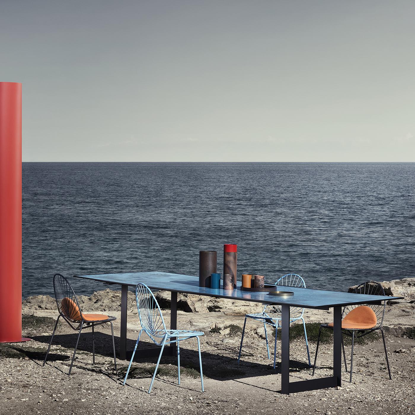 Entirely crafted of steel, this indoor-outdoor dining table boasts a simple and elegant silhouette composed of rectangular legs sustaining a rectangular top made of steel and completed with a sheet of enameled stoneware (5 mm-thick) in a bold