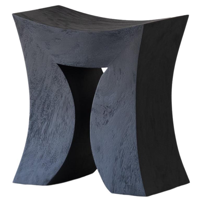 Torii, tabouret en bois noir brut en forme de cosse de singe