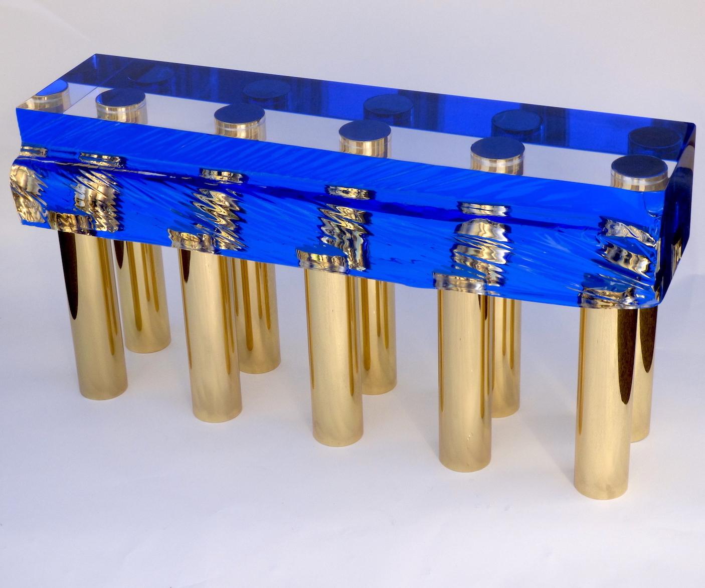 Une belle banquette ou table basse en plexiglas transparent de couleur bleue et avec dix pieds en laiton conçue par Studio Superego pour les éditions Superego, en 2018.

Biographie :
Les éditions Superego sont nées en 2006, menant une activité