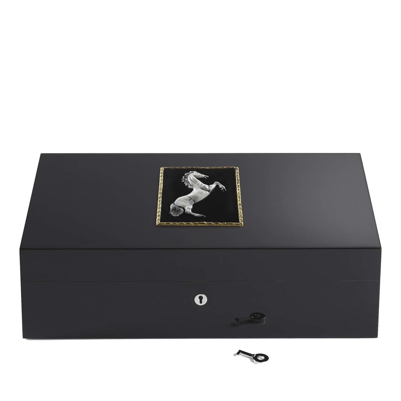 This sophisticated wooden humidor contains up to 110 cigars. Its structure painted black boasts a surface smooth to the touch. A polished decoration gracing the lid depicts a fierce horse with a silver finish, while the black background is enclosed